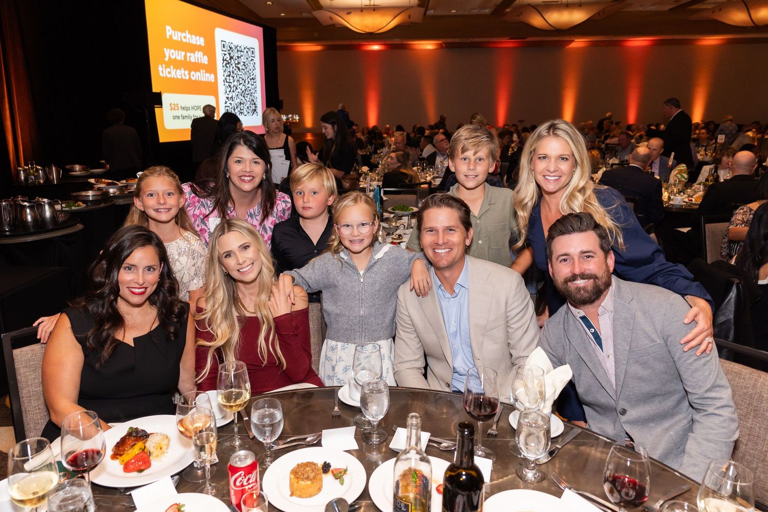 Group of attendees smiling together at formal dinner event.