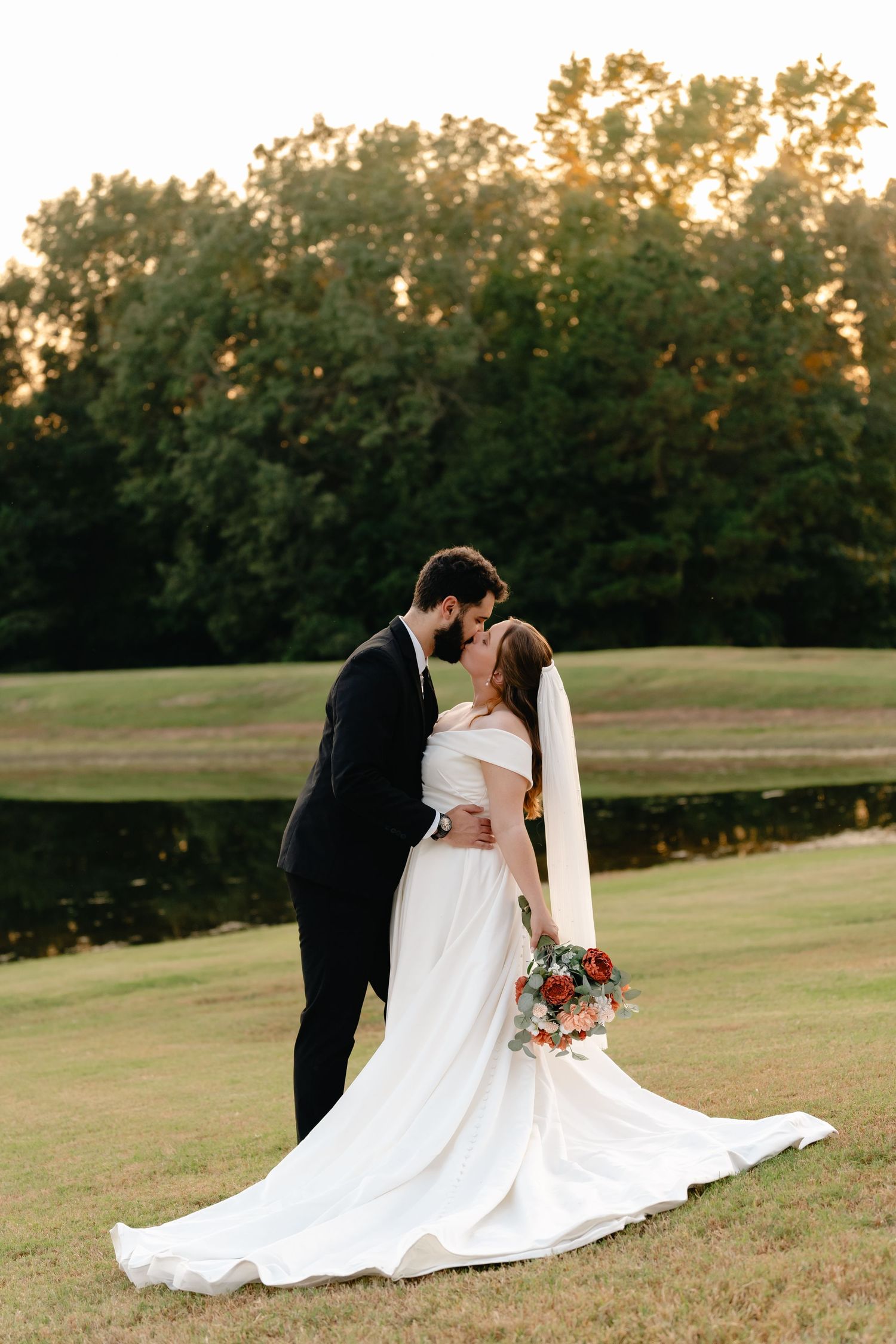 Romantic wedding portraits on a rolling lawn with dramatic sunset lighting in the background.