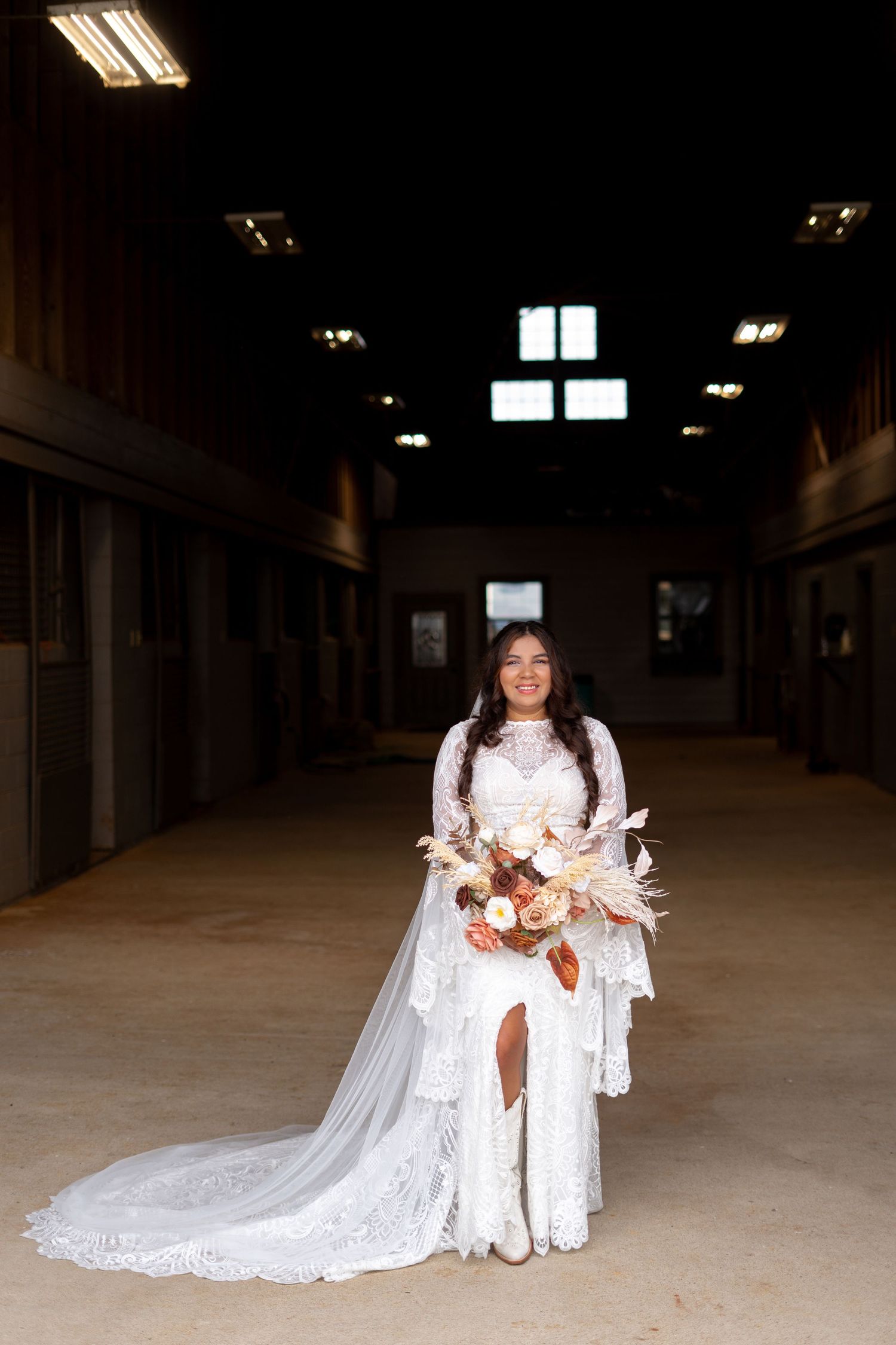 Wedding party posing in indoor venue with white lace dresses and bouquets.