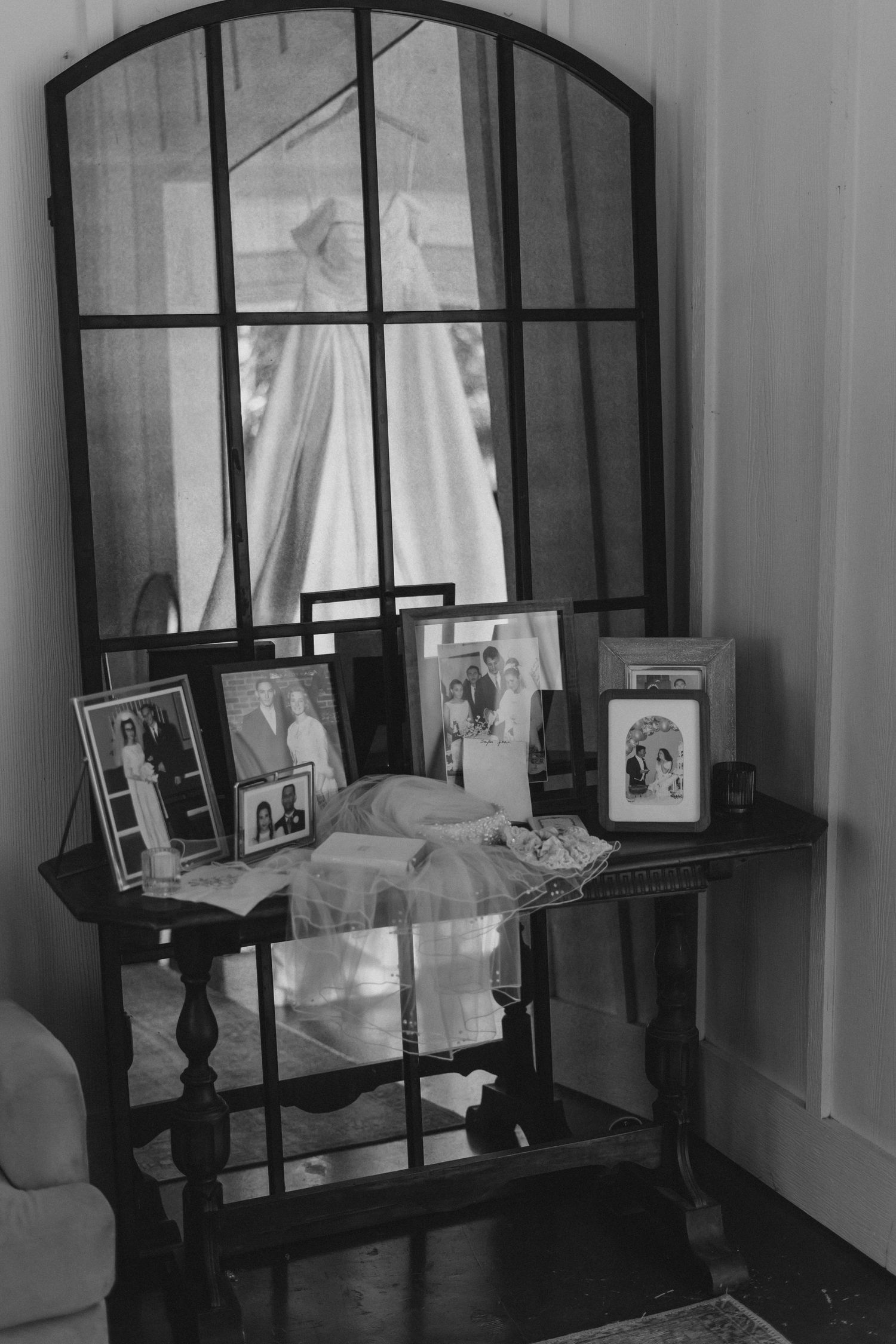 A vintage console table with framed photographs and a mirror in a black and white setting.