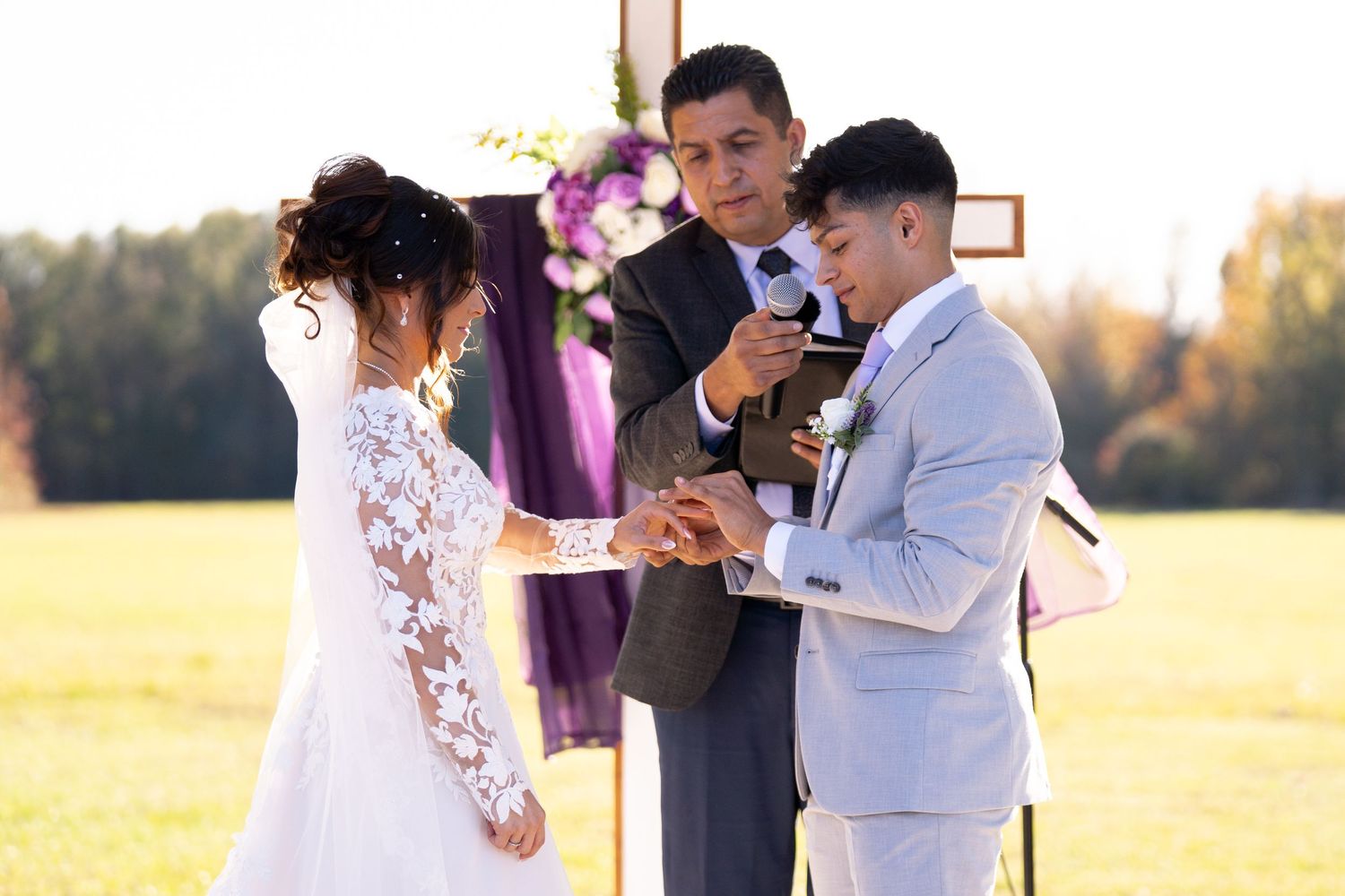 An outdoor wedding ceremony taking place with formal attire against a natural backdrop.