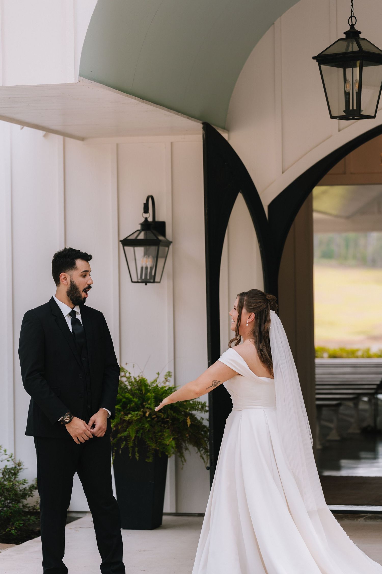 Wedding couple shares intimate first look moment under white columned porch.