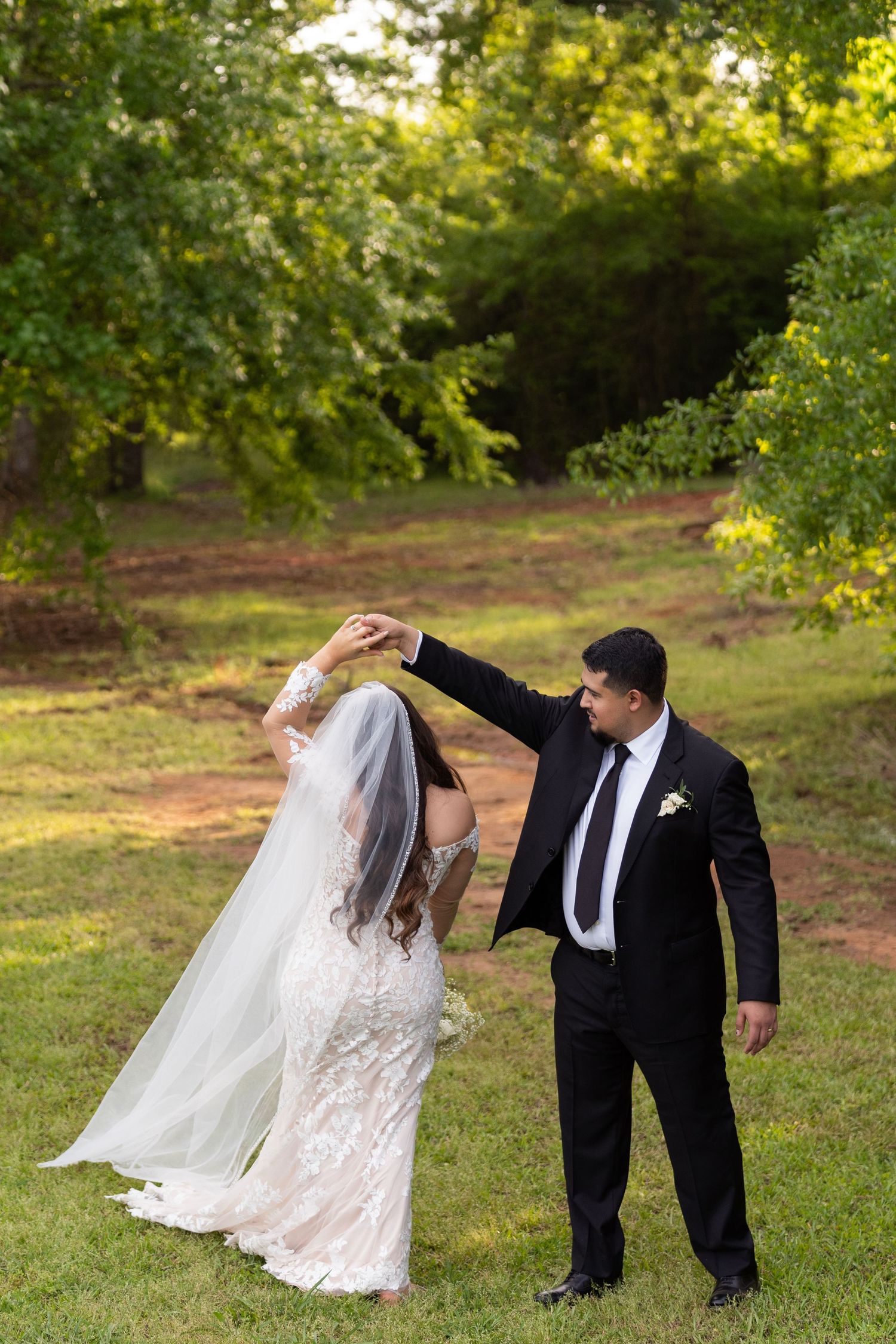 A couple in wedding attire playfully leans and poses together in a series of photos on a grassy outdoor setting.
