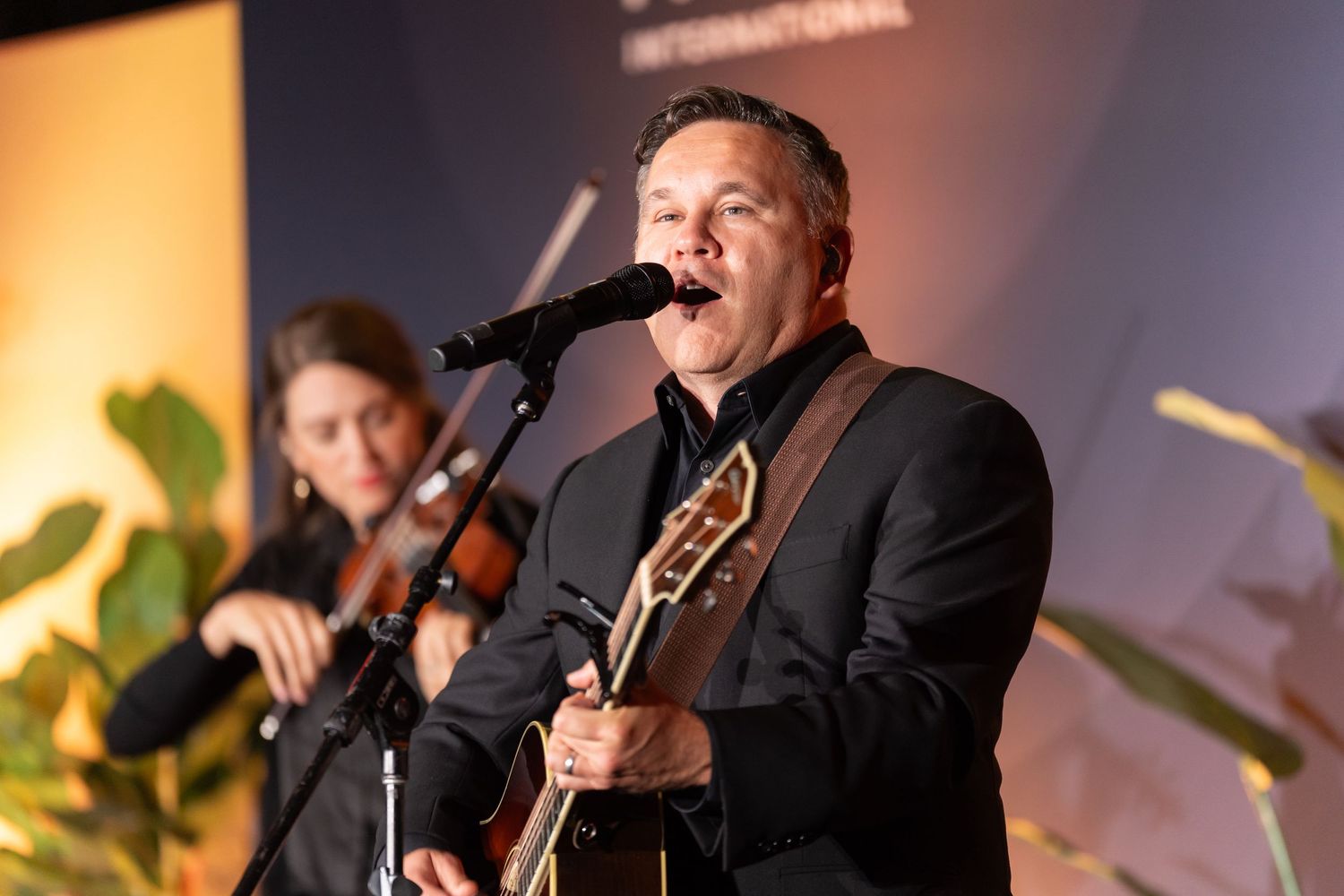 Musicians performing on stage with dramatic lighting and instruments.