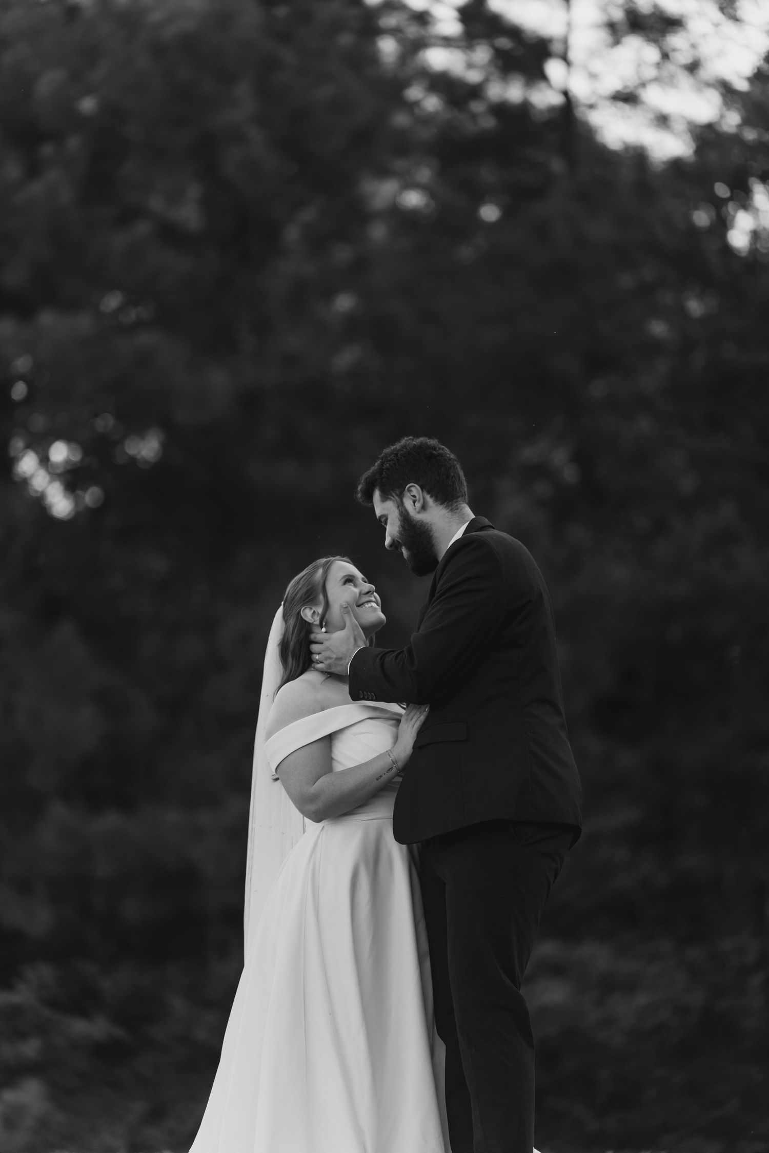 A black and white wedding portrait shows a tender embrace between the newlyweds.