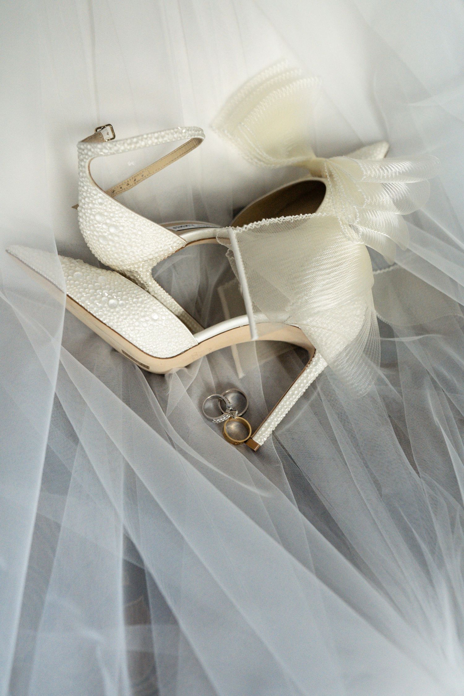 White lace bridal heels arranged artistically with flowing tulle fabric.