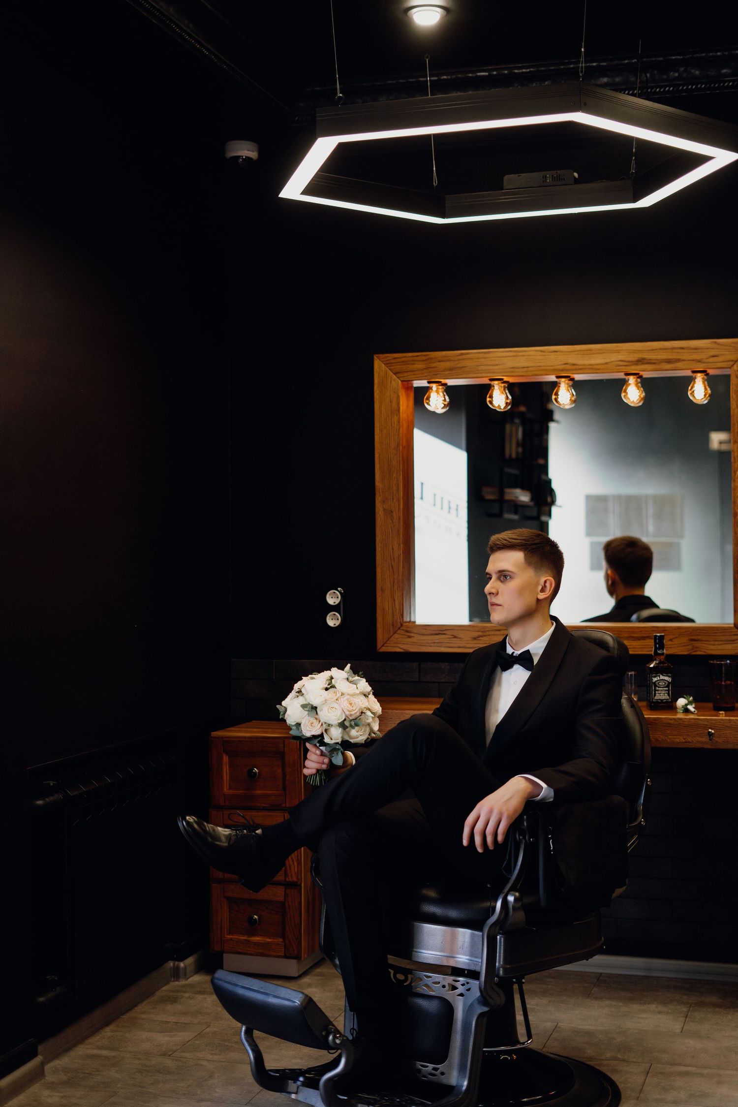 A series of dark, moody interior shots in a barbershop featuring black leather chairs and wooden accents.