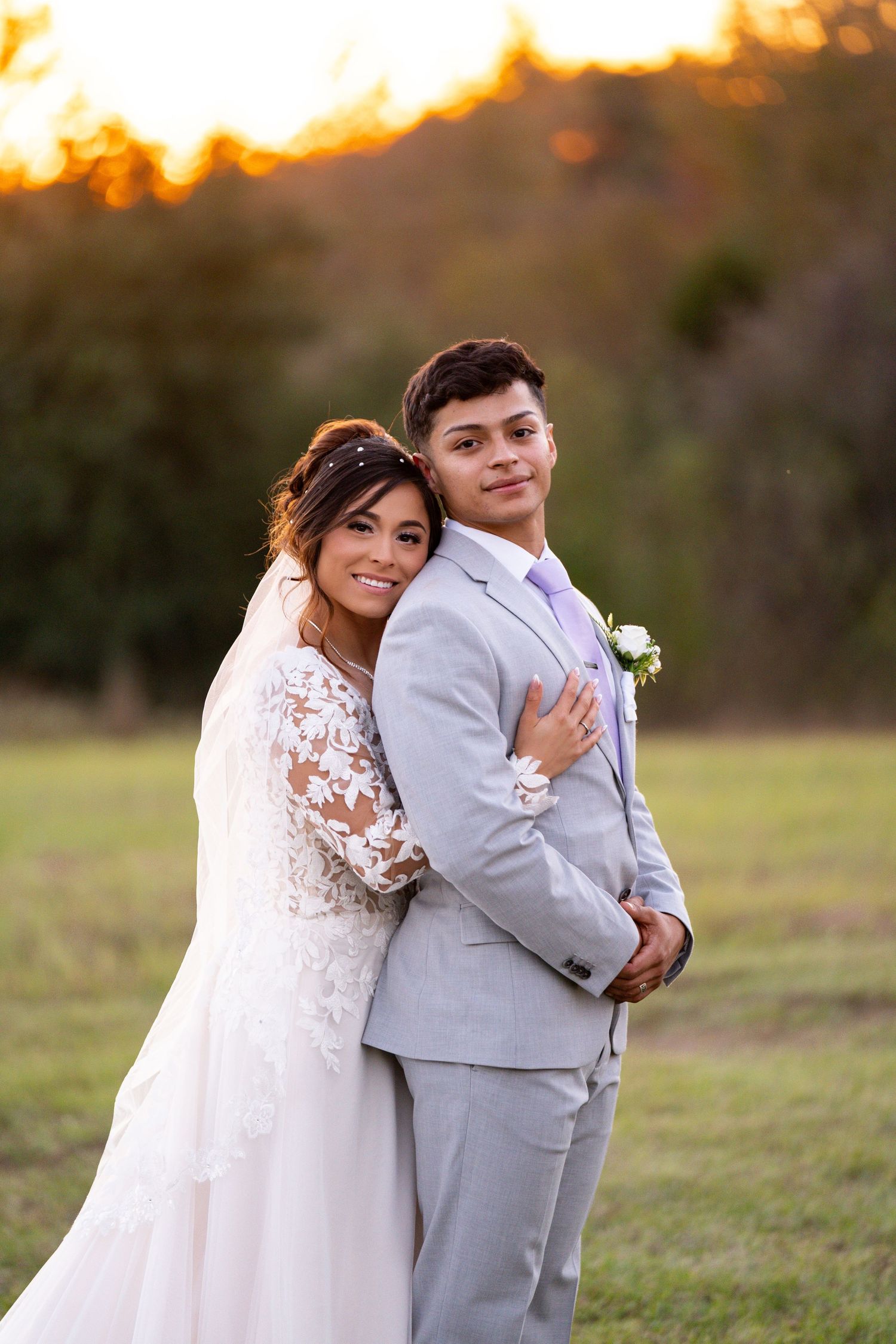 Golden hour wedding portraits with couple embracing in field at sunset.