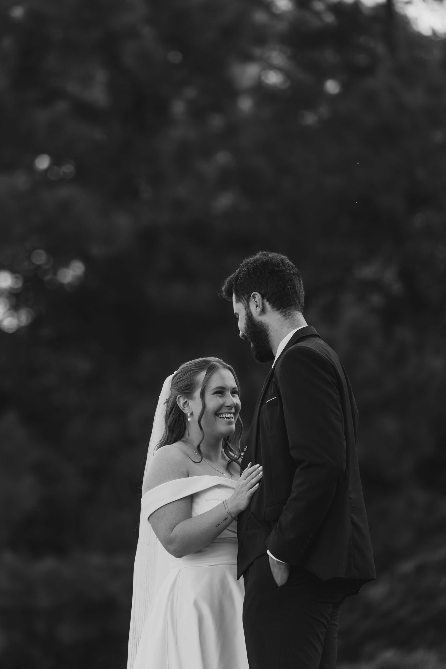A joyful wedding moment captured in black and white as the couple laughs together outdoors.