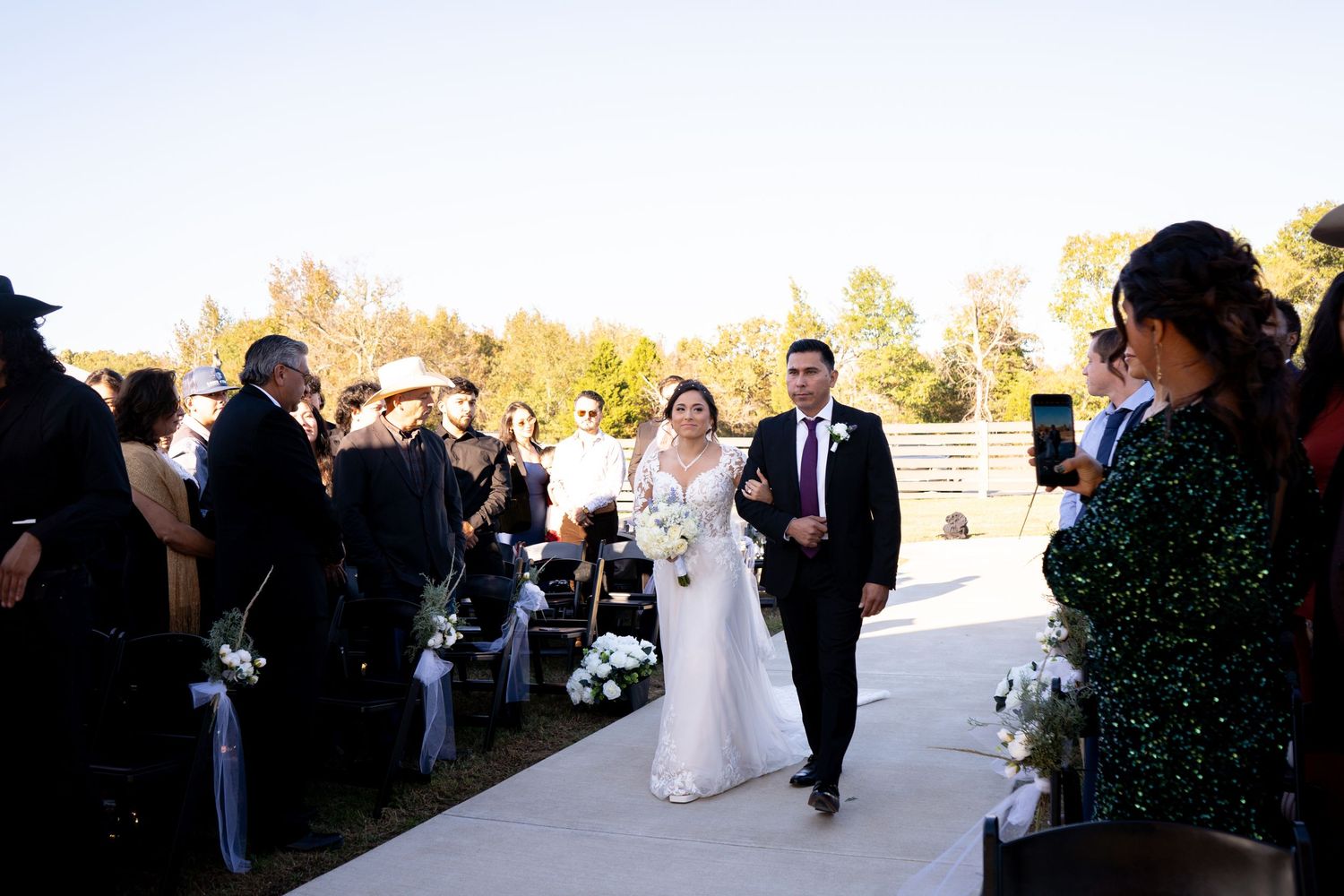 Wedding ceremony guests gathered outdoors on a sunny autumn day.