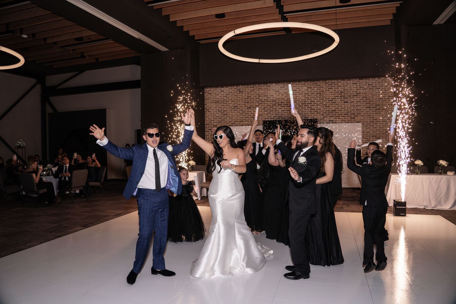 Wedding celebration at an industrial venue with exposed brick walls, modern lighting and sparkler effects on the dance floor.