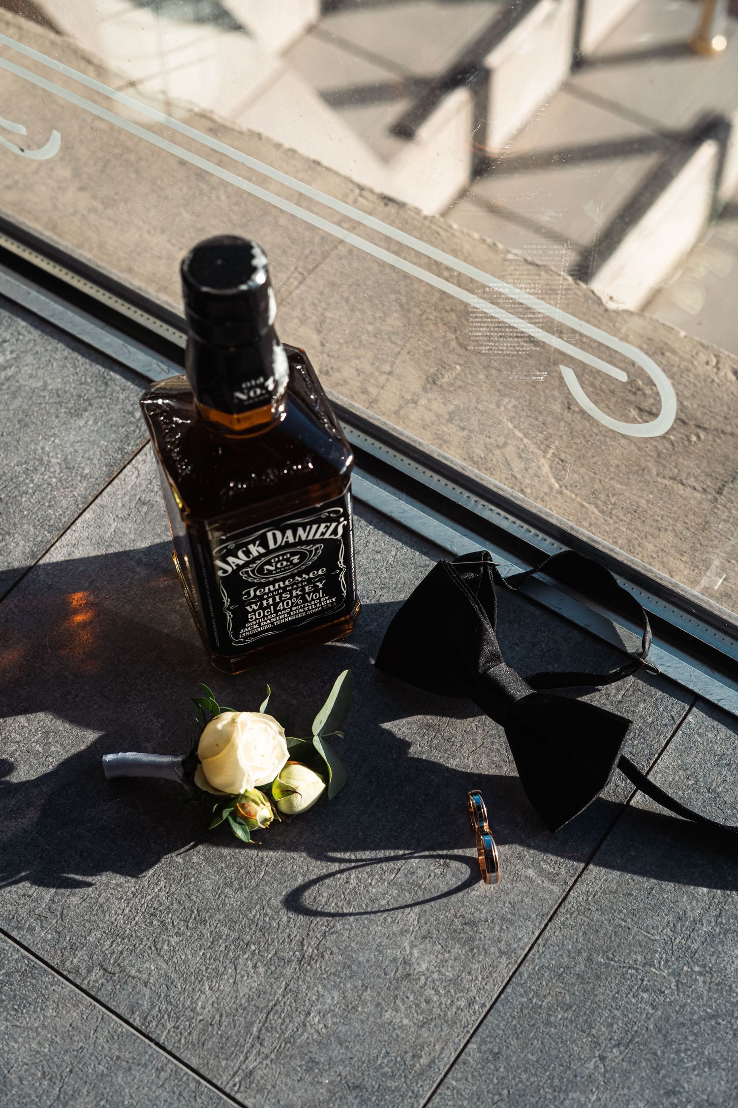 A sequence of four photos showing a Jack Daniel's whiskey bottle casting dramatic shadows on a concrete surface.