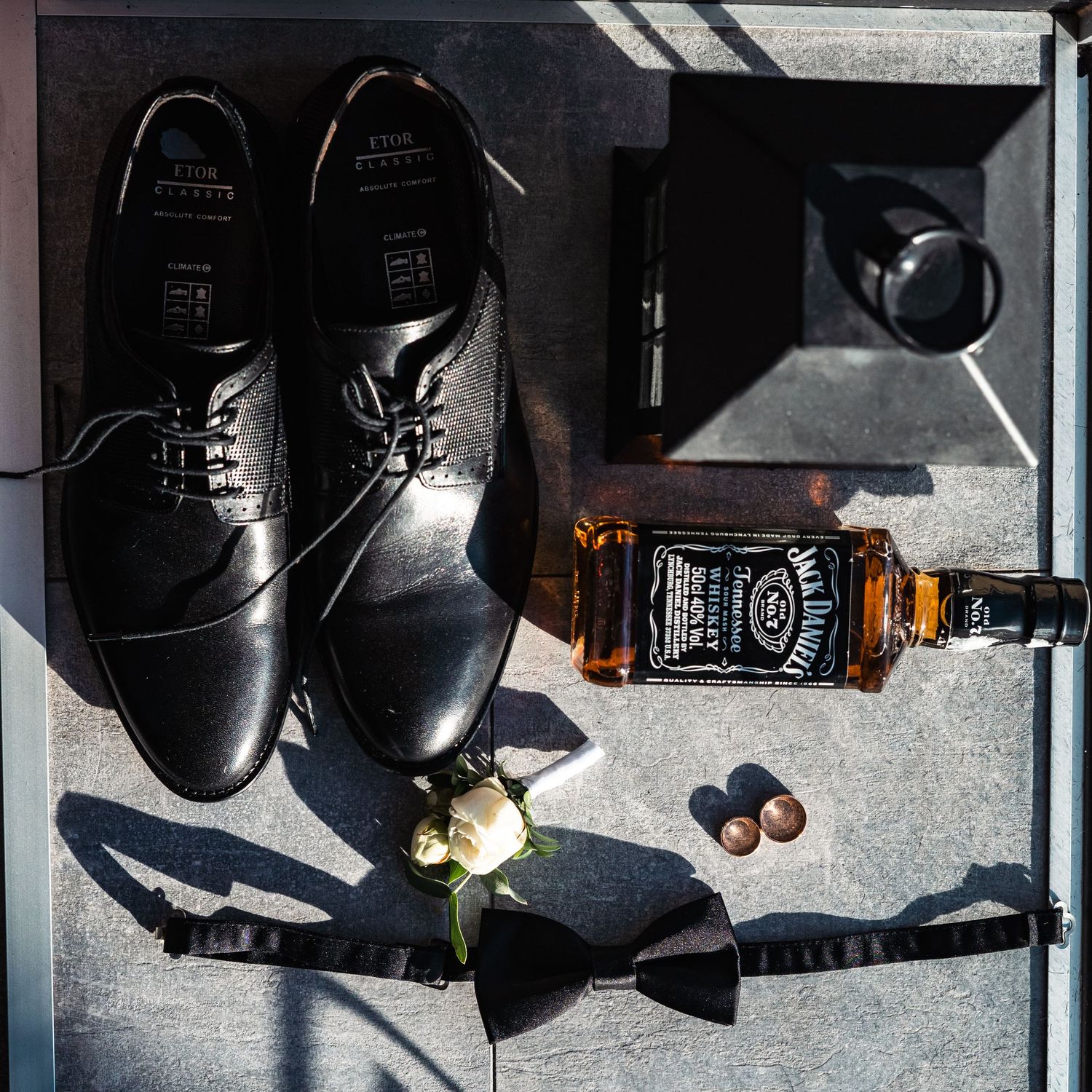 Black leather dress shoes and whiskey bottles arranged in a sequence of artistic still life compositions.
