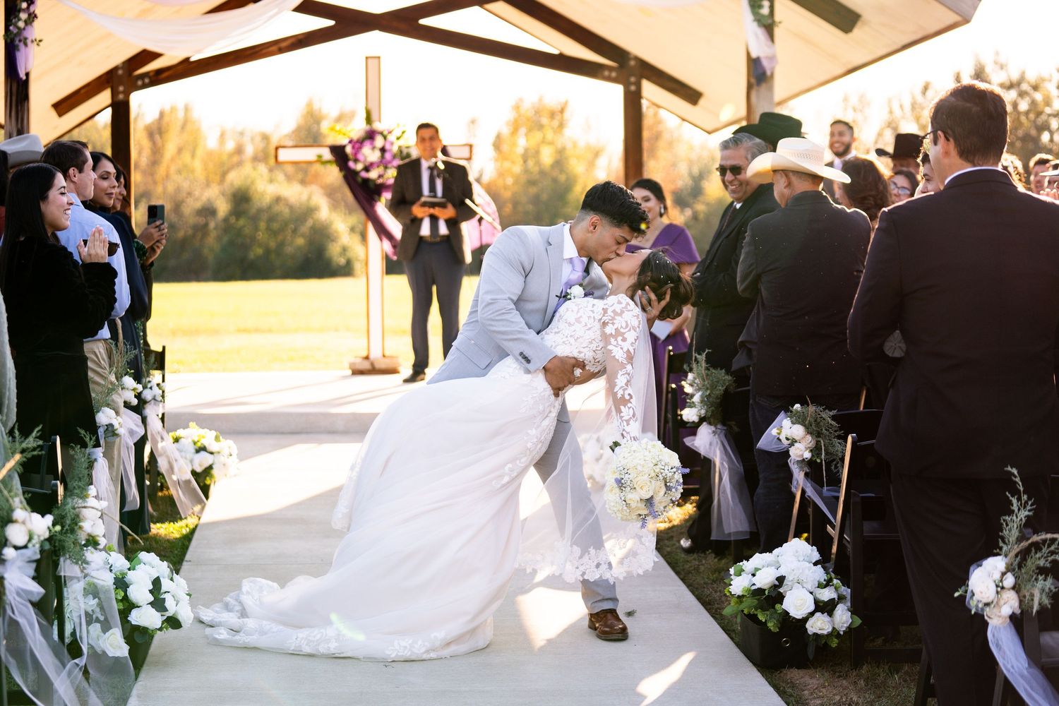 Outdoor wedding ceremony setup with white floral decorations and natural autumn backdrop.
