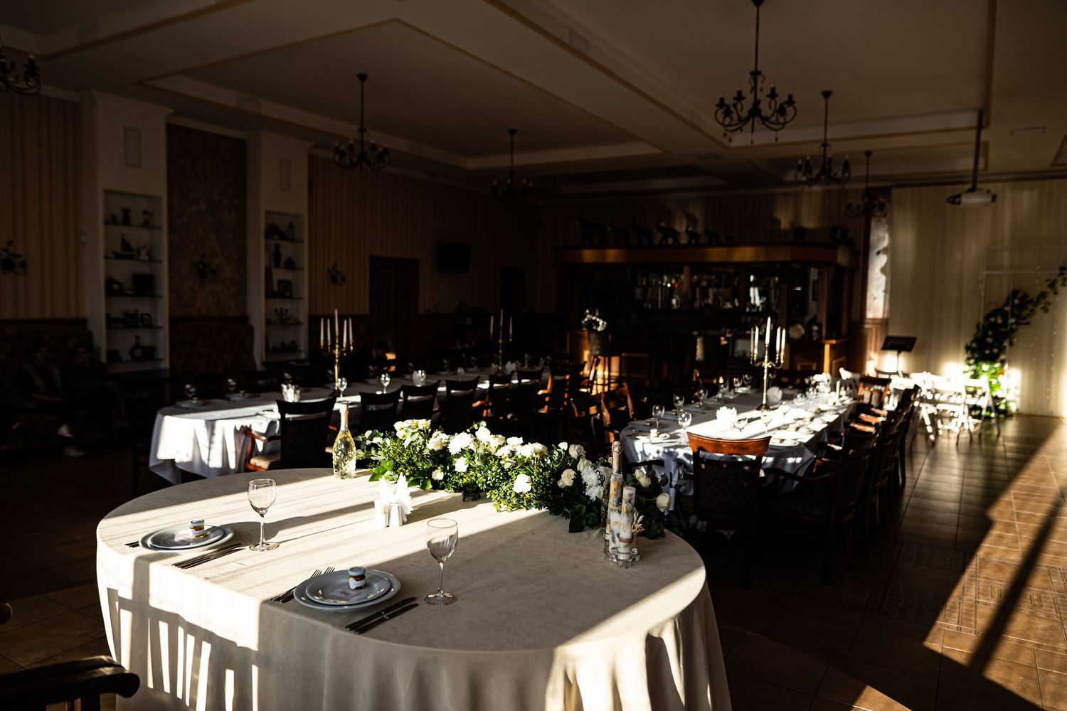 Dimly lit restaurant interior with white tablecloths and elegant place settings creates an intimate dining atmosphere.