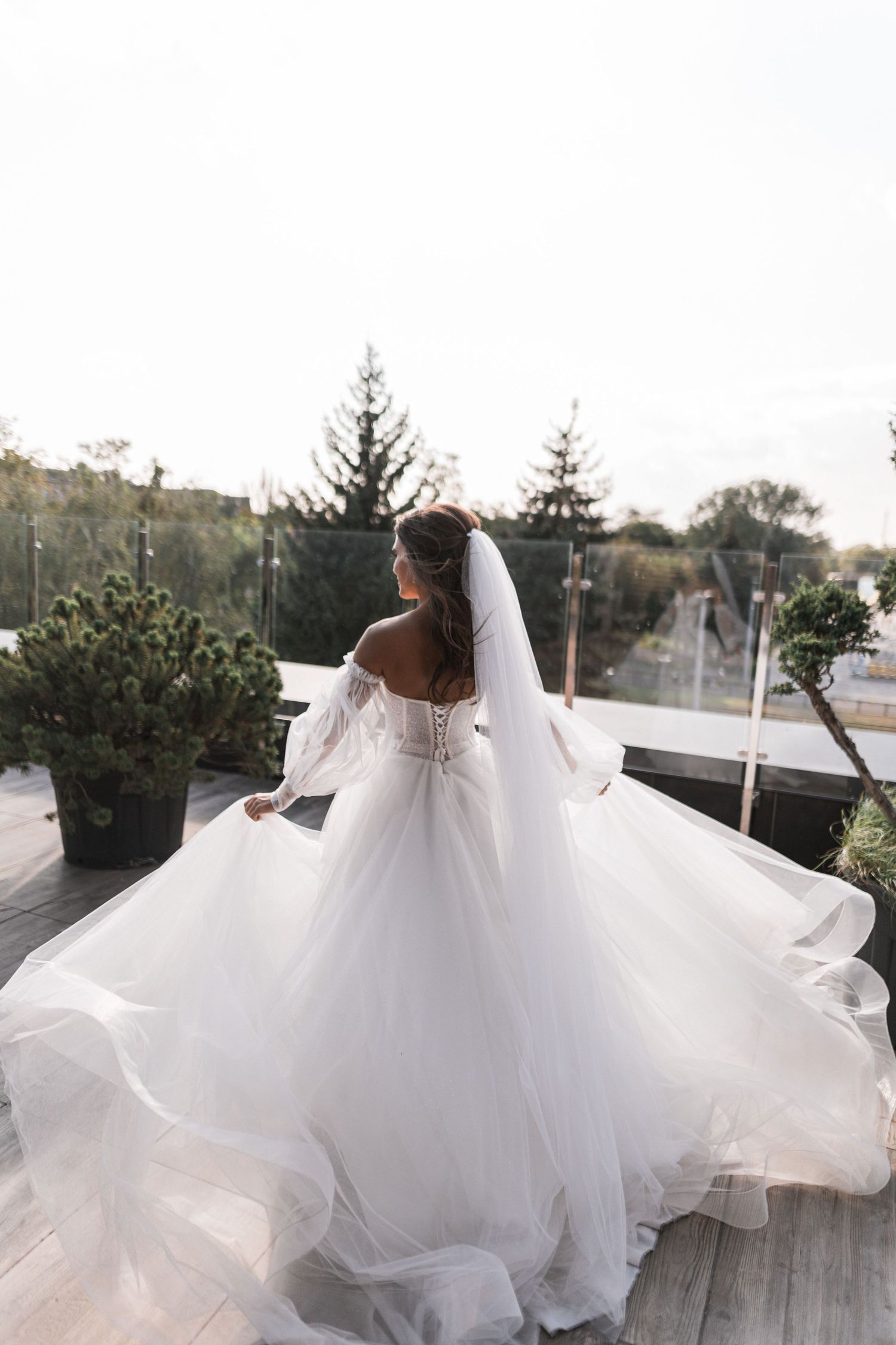 A bride in a flowing white wedding dress twirls gracefully on a wooden deck, creating a beautiful swirling effect.