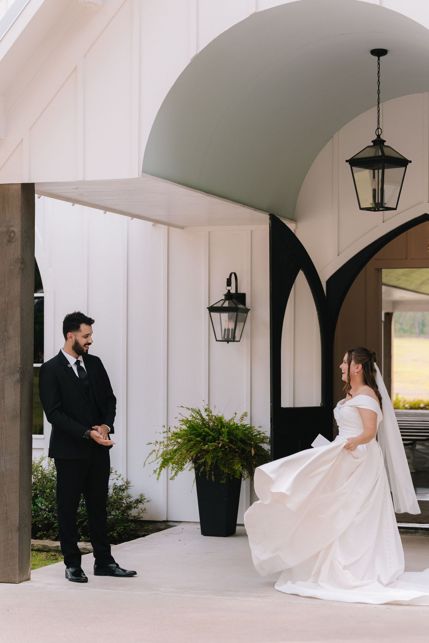 First look wedding photos showing couple's reactions under elegant white archways with lanterns.