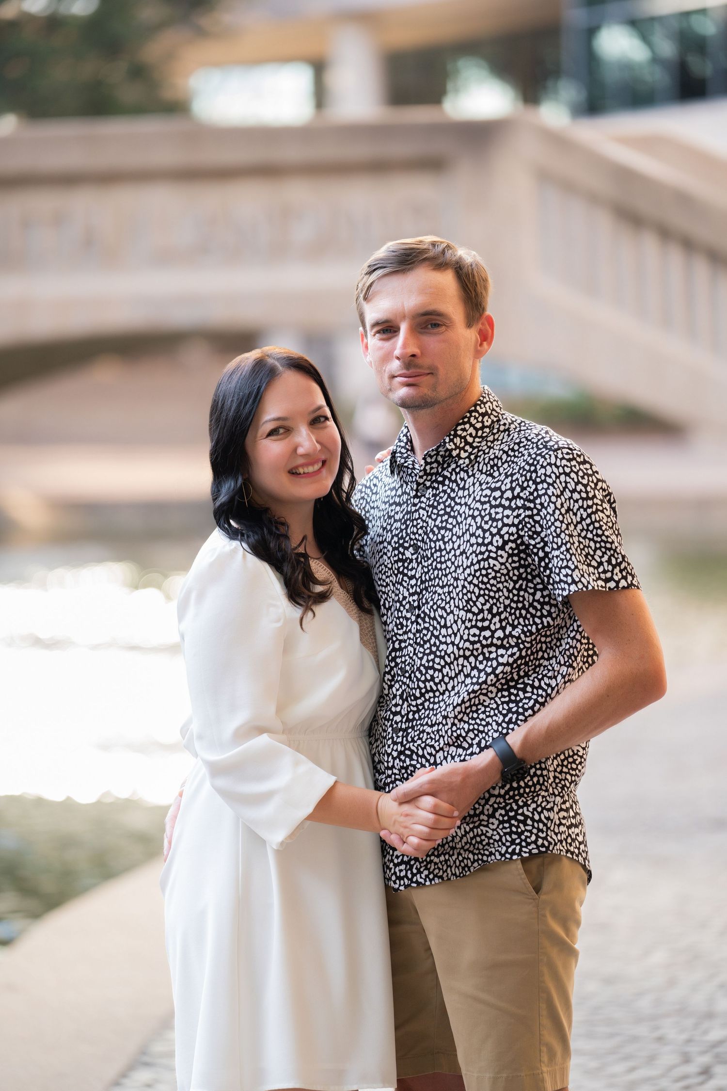 Couple poses playfully near an urban setting, with one wearing a white top and the other in a leopard print shirt.