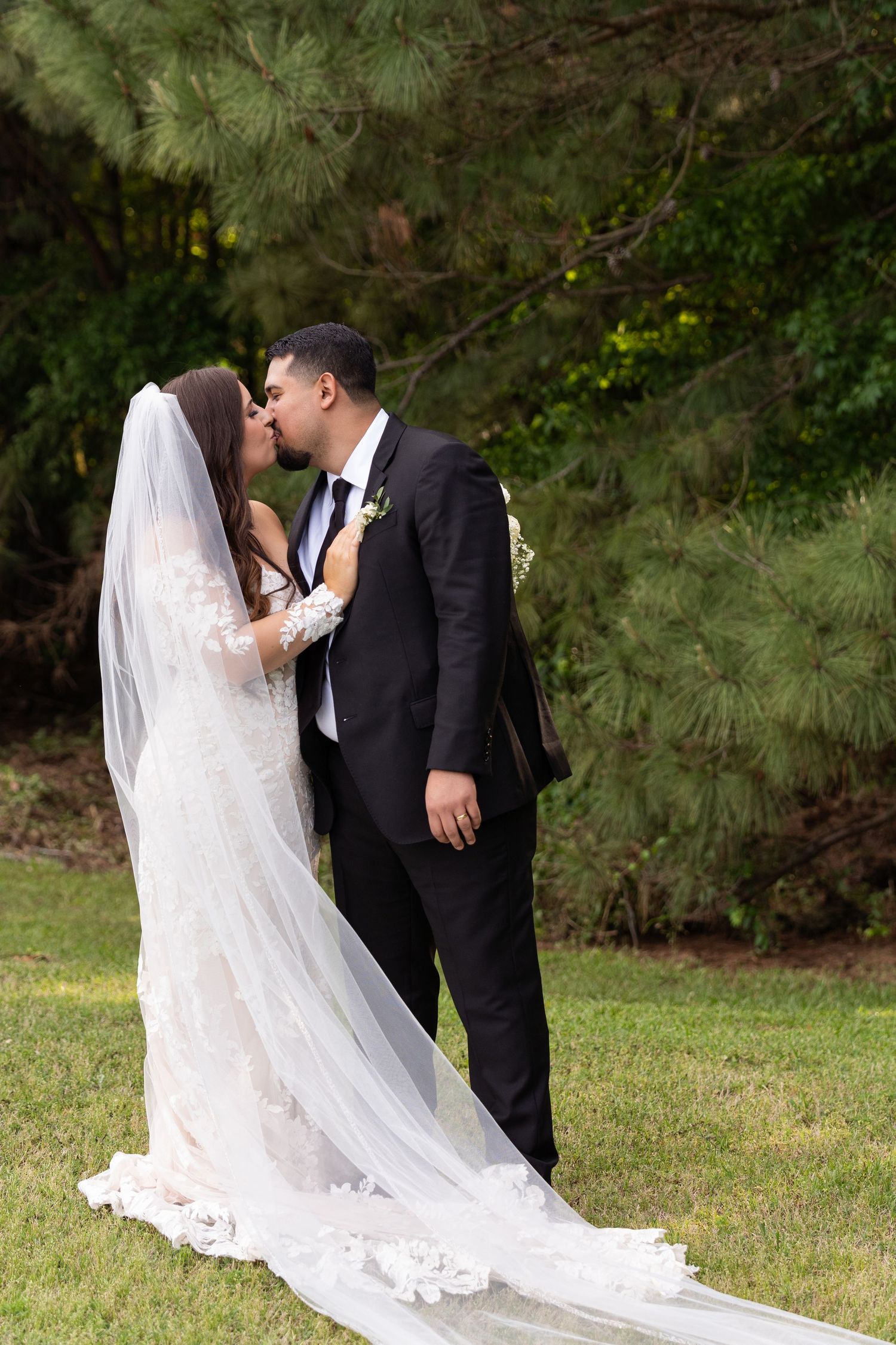 Romantic wedding couple shares intimate moments in an outdoor garden setting with a flowing white veil.