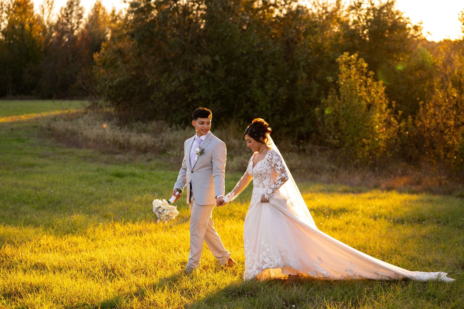 Sunset wedding photos in golden field with flowing white dress catching evening light.