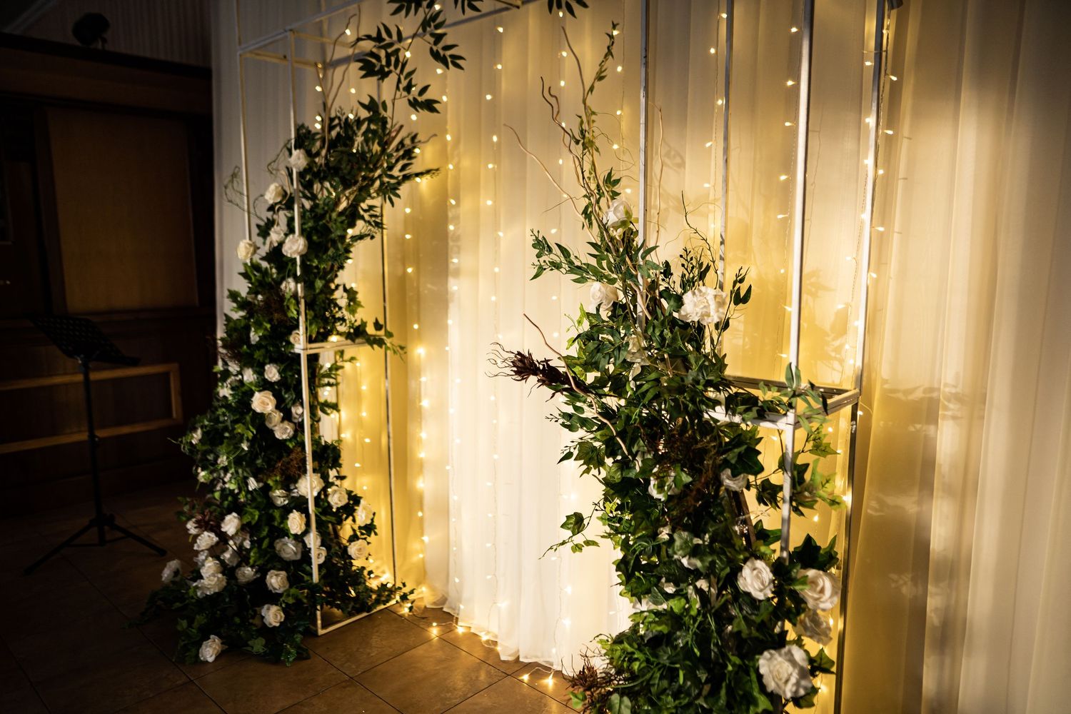 Decorative string lights illuminate a wall with cascading greenery creating a warm and enchanting ambiance.