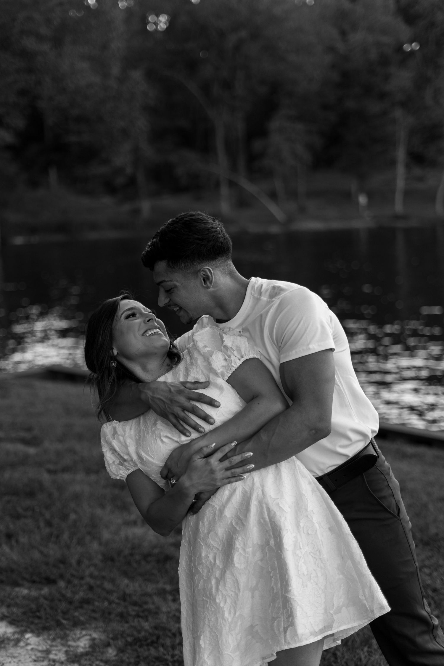 Black and white photo shows couple's intimate dance pose near water.