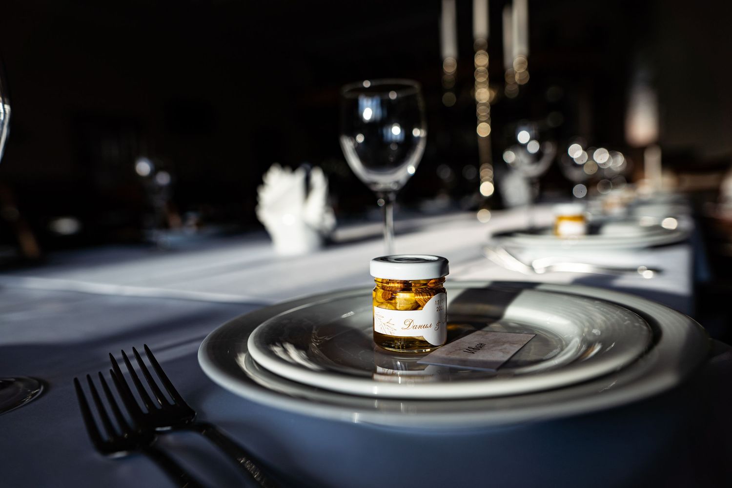 Elegant table setting with wine glasses and a layered dessert shot in moody lighting.
