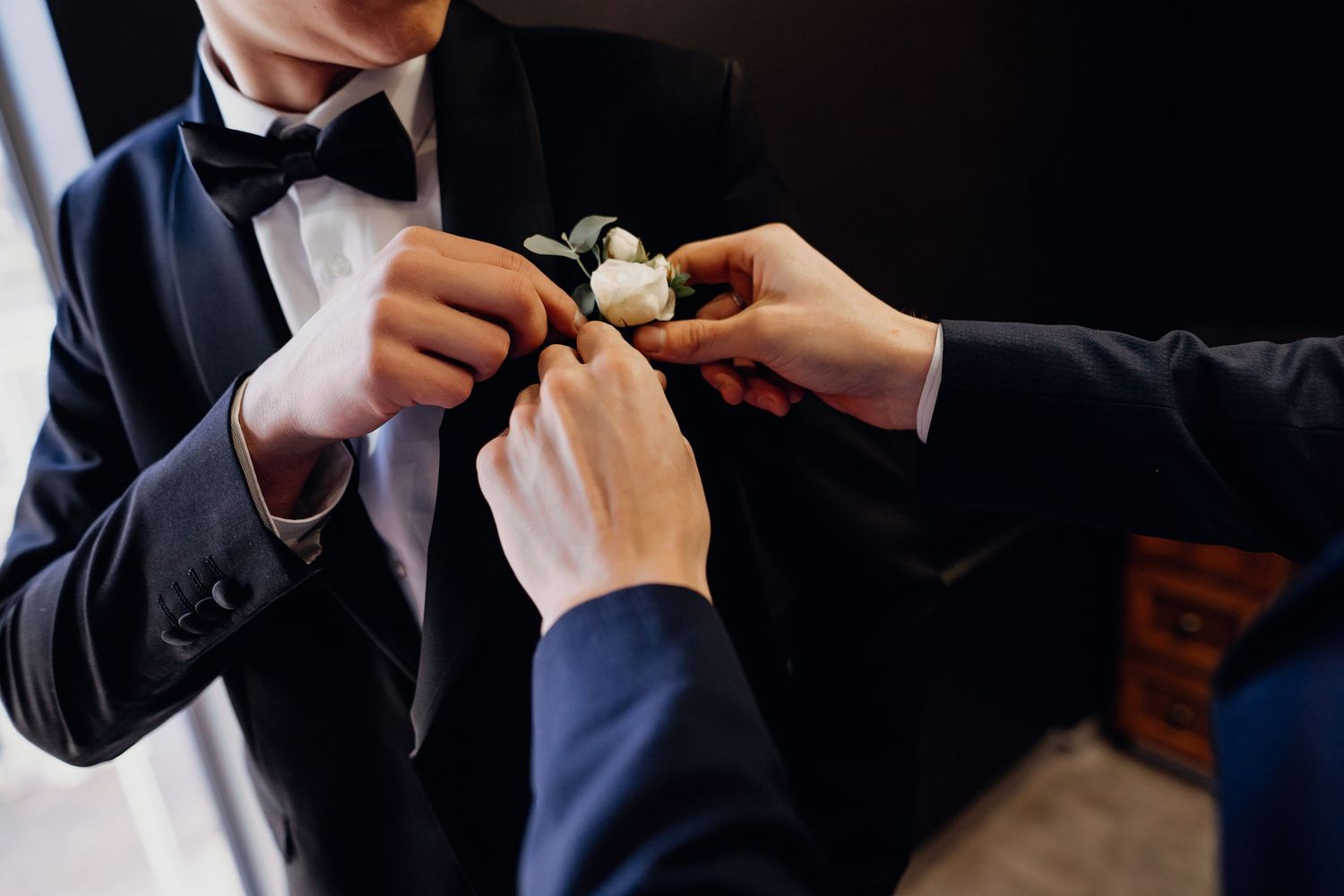 A group of people in dark suits examine small objects in their hands during a formal gathering.