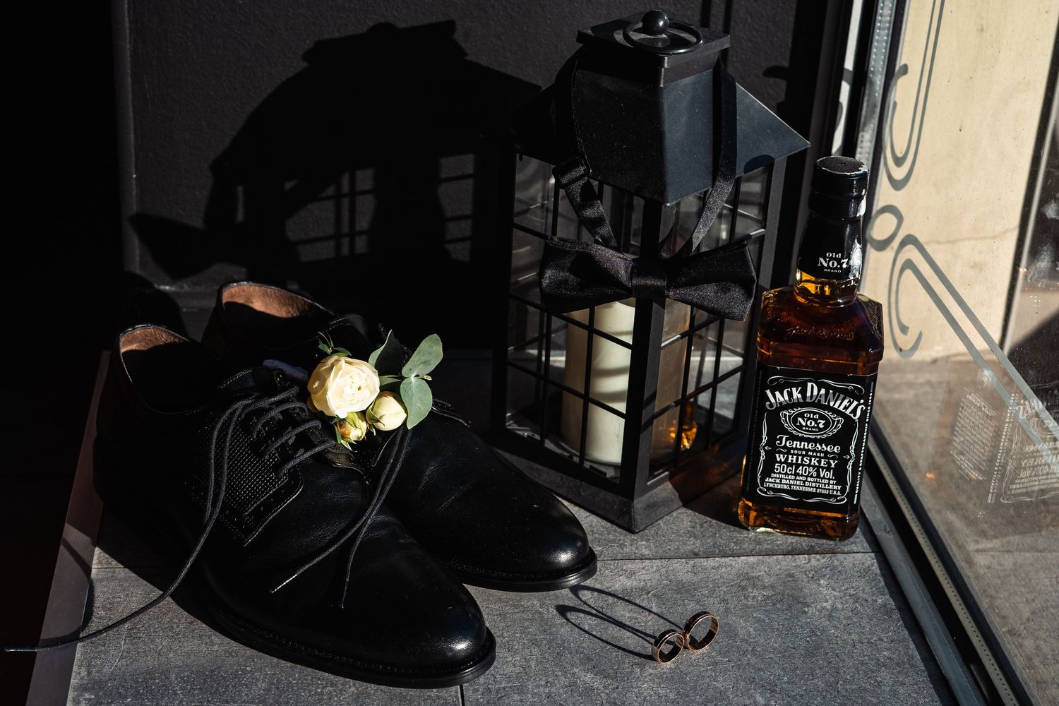 A collection of dark glass bottles and barware arranged on a wooden surface in dim lighting.