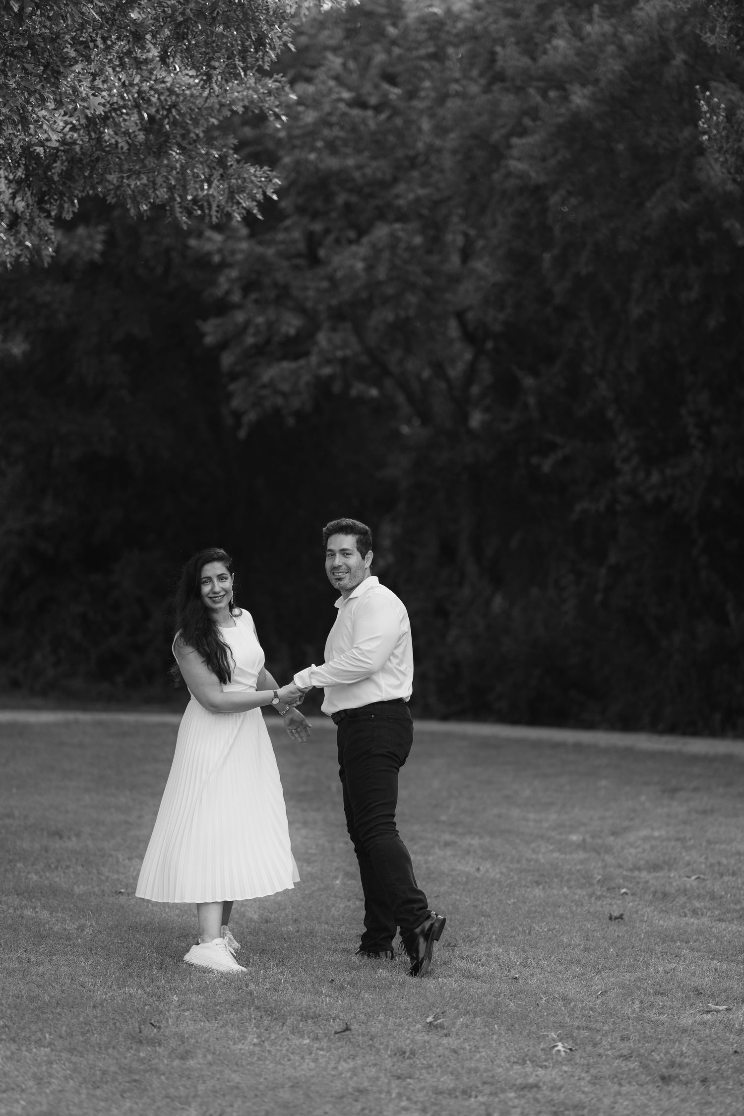 Black and white photos of a couple dancing and twirling on a grassy field.