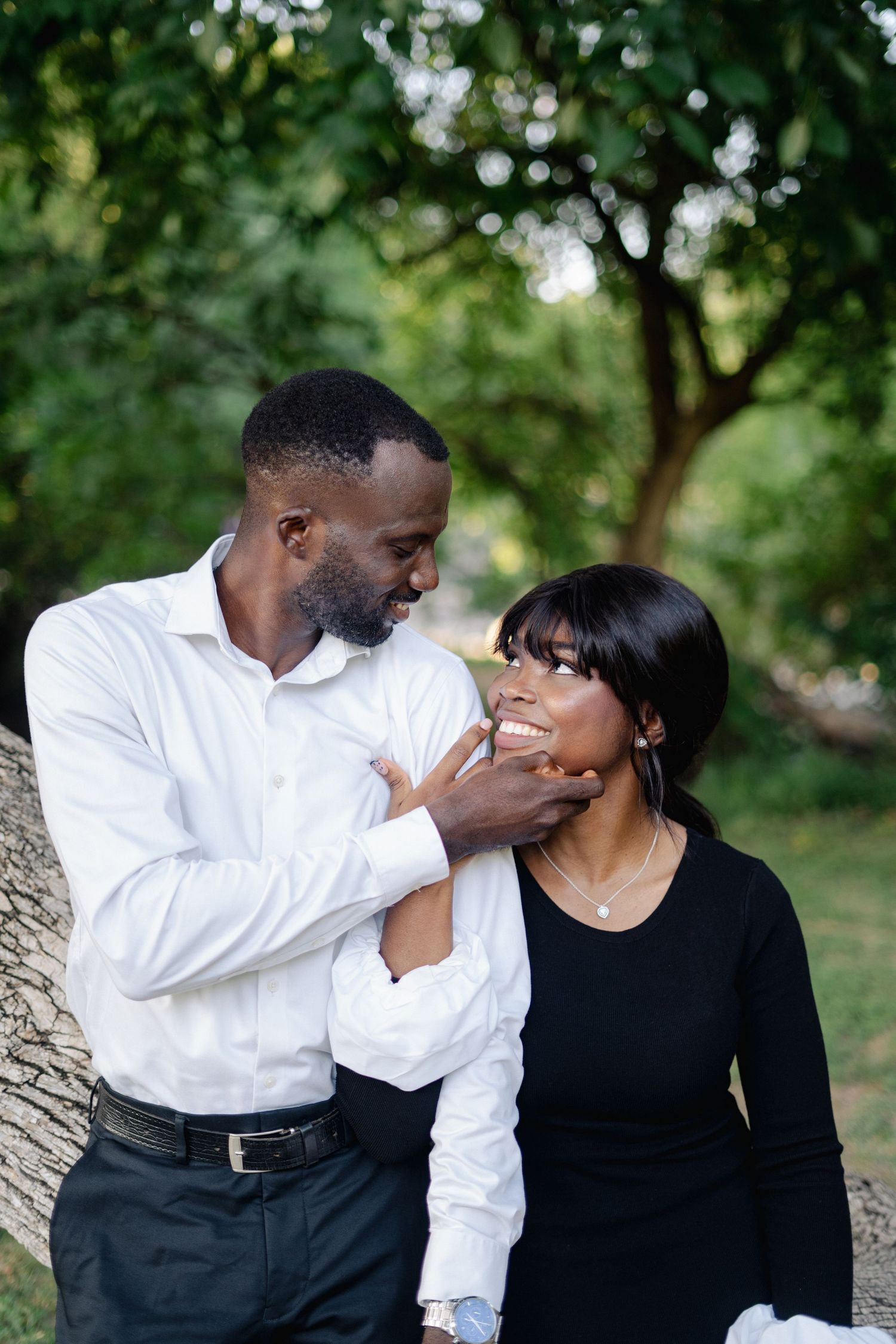 Couple in contrasting black and white outfits sharing intimate moment outdoors.