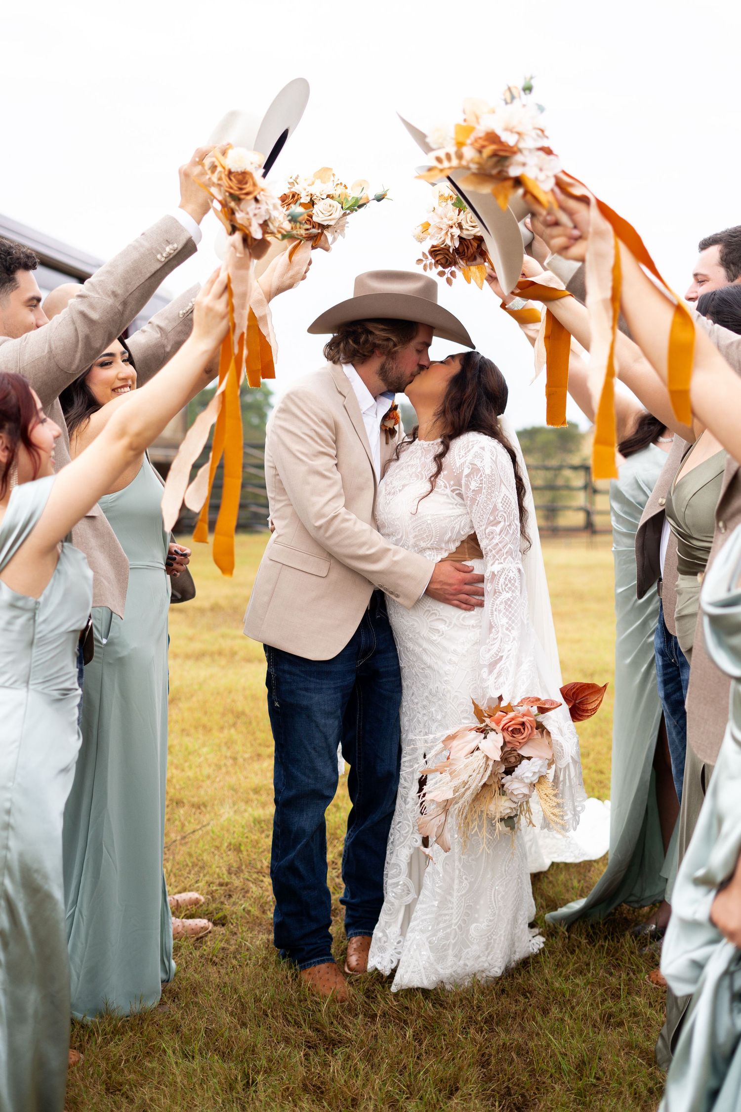 Wedding party in light blue dresses toasting with drinks outdoors in a sunny field.