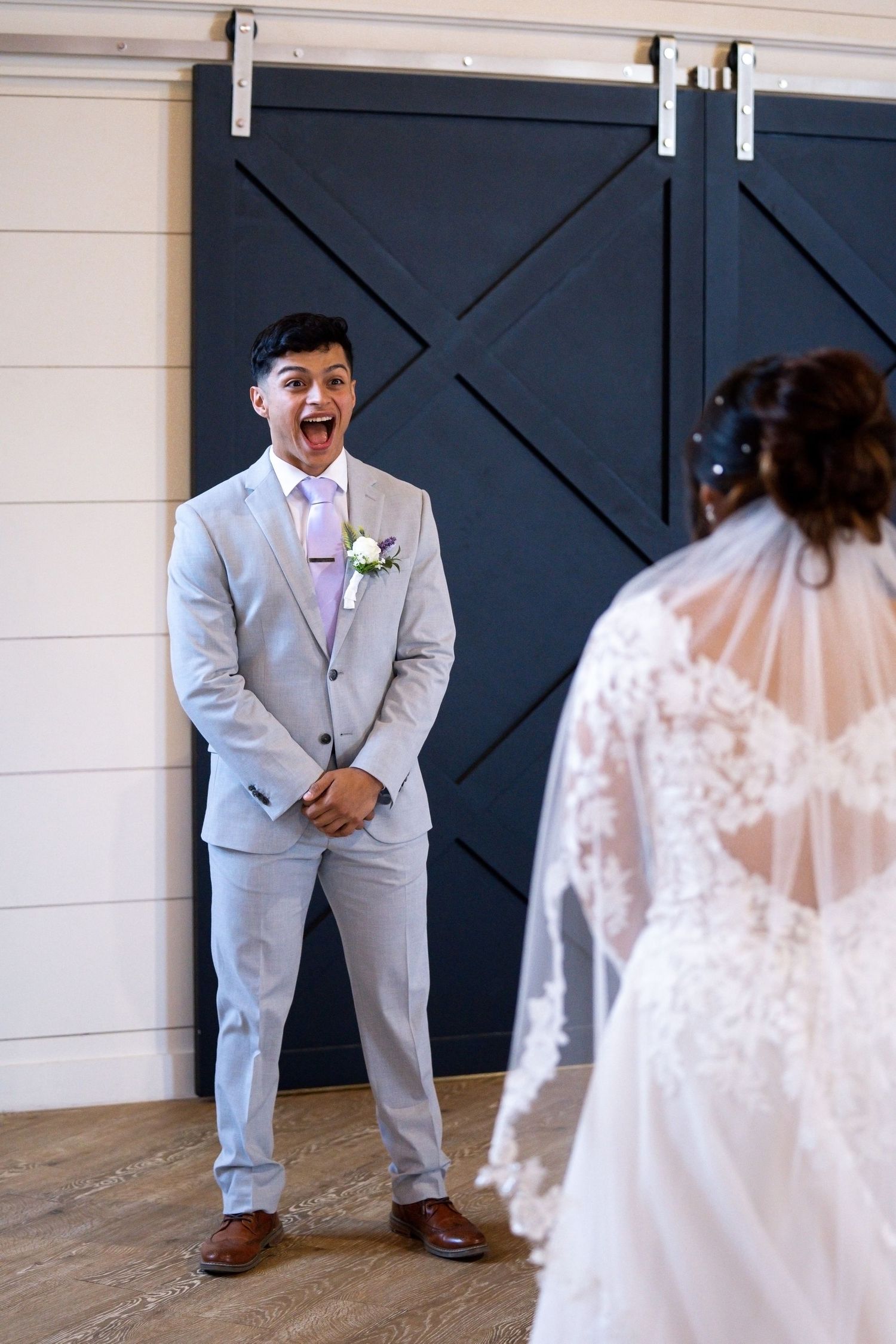 Wedding first look moment with bride in lace gown and groom in light gray suit.