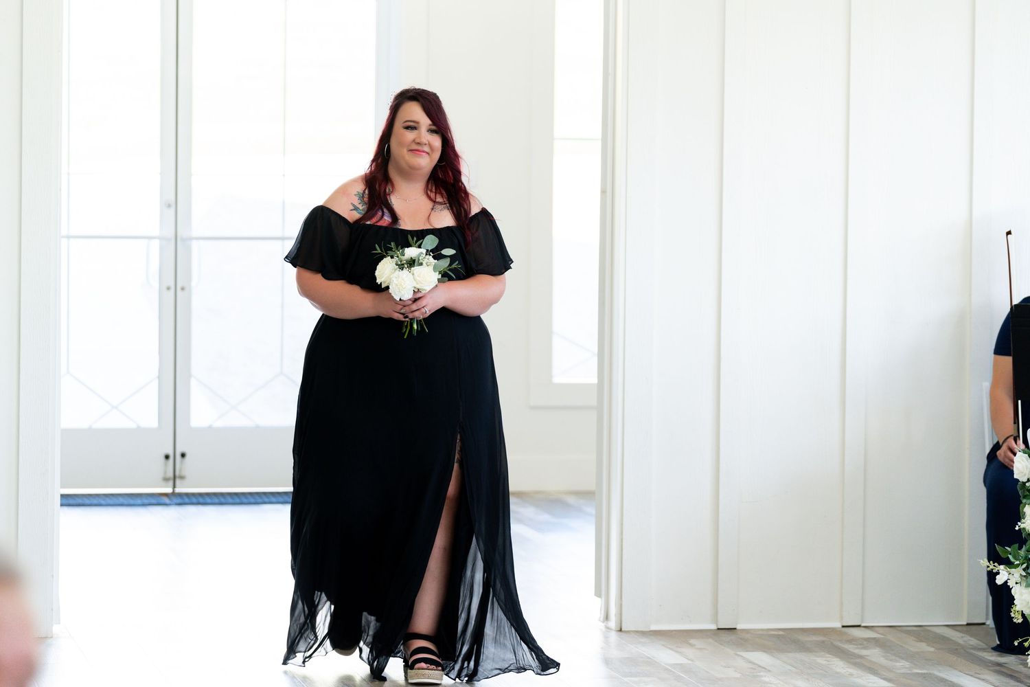 A woman in a black dress poses in various positions against a white wall during a photo shoot session.