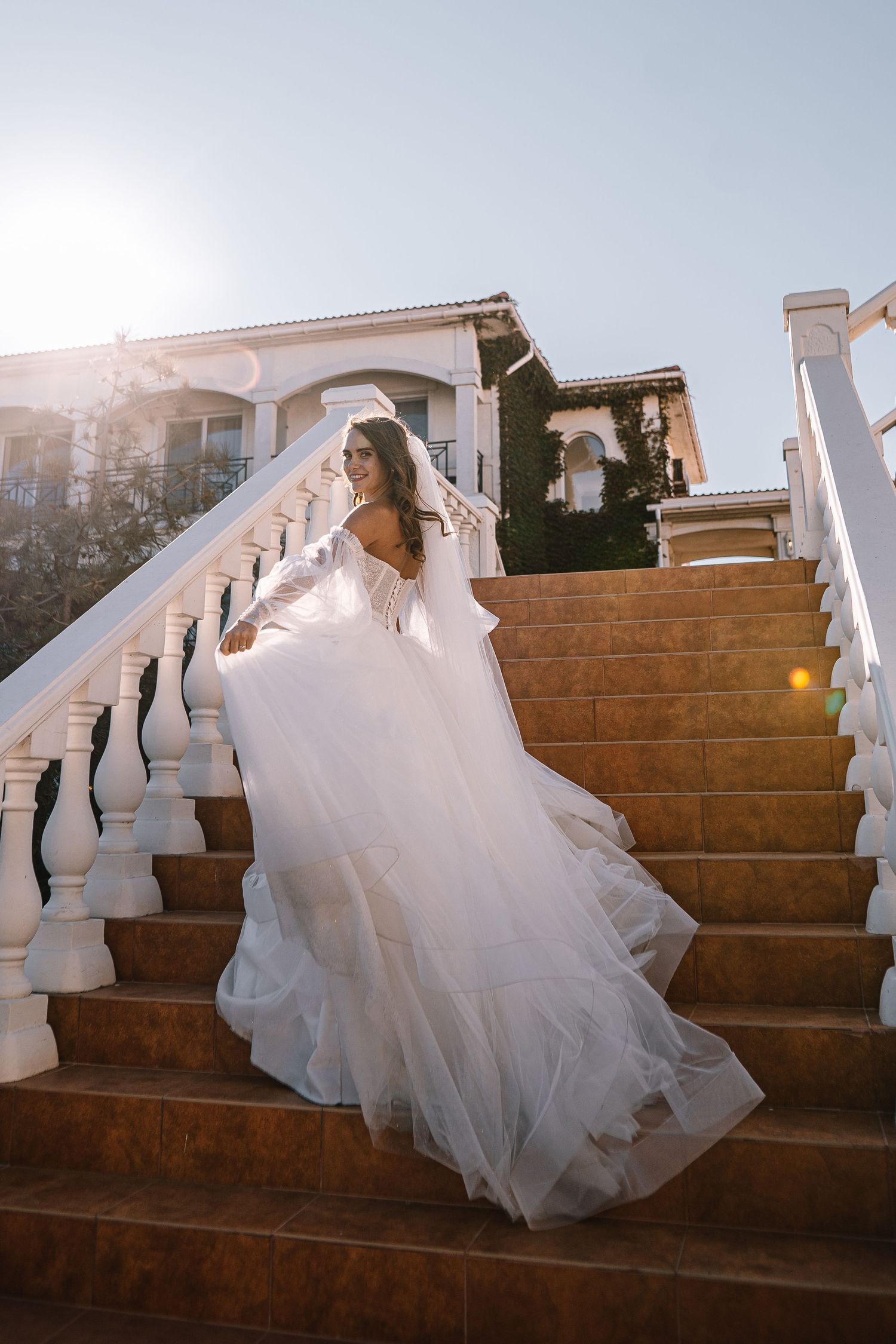 A sequence of photos showing a bride in a flowing white gown descending stone steps at dusk.