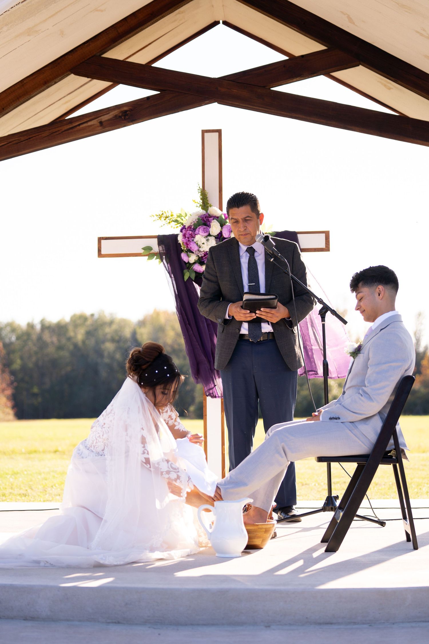 Romantic wedding photoshoot under a wooden pavilion with dramatic lighting and shadows.