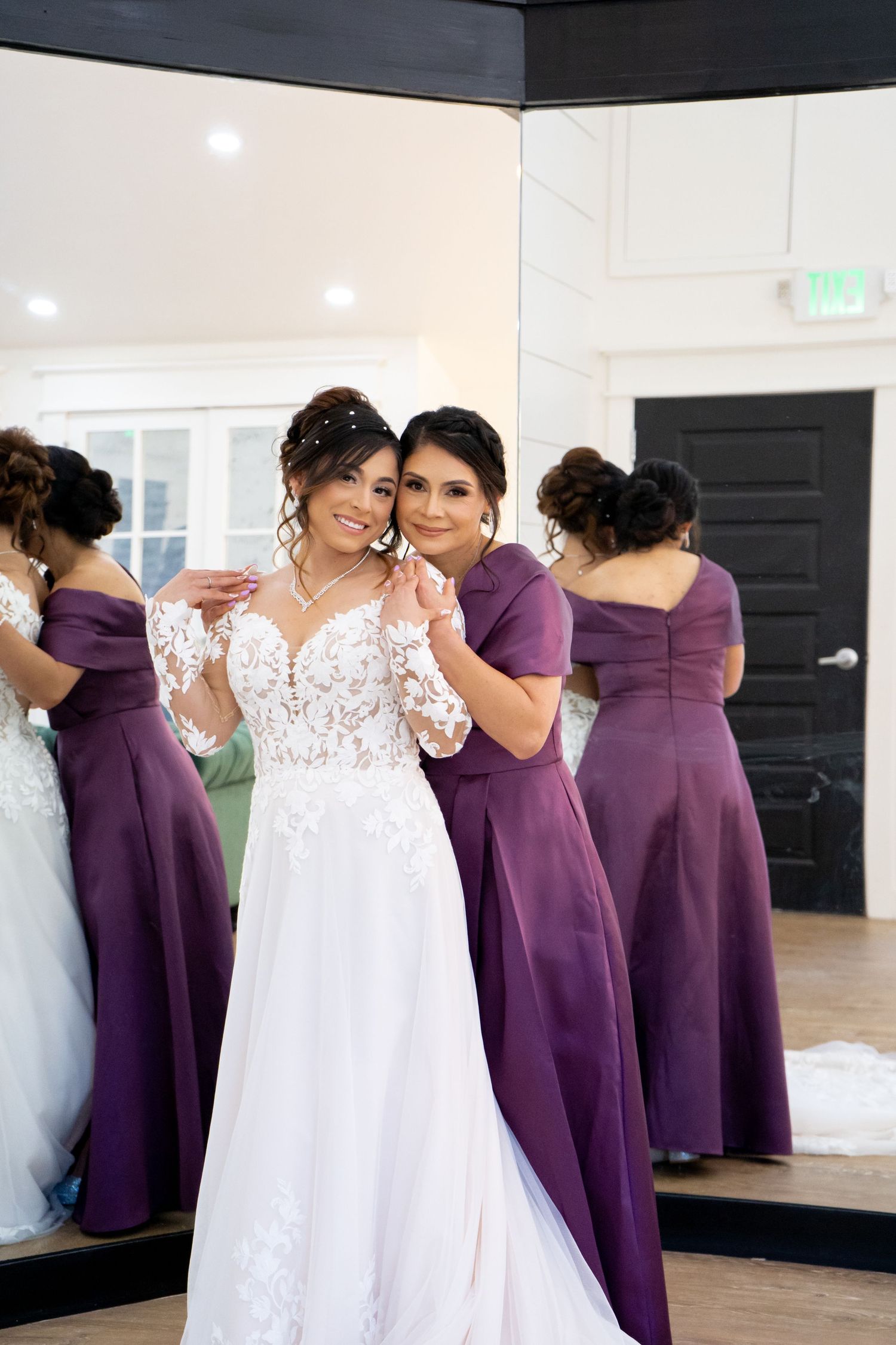 Bridesmaids in elegant purple dresses help with wedding preparations in a bright modern room.