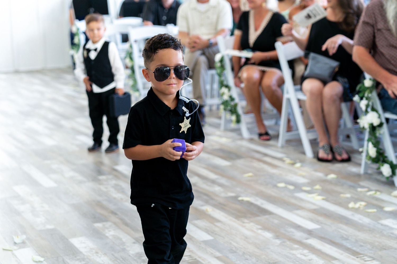A small child in black clothing dances energetically on a tiled floor during a celebration.