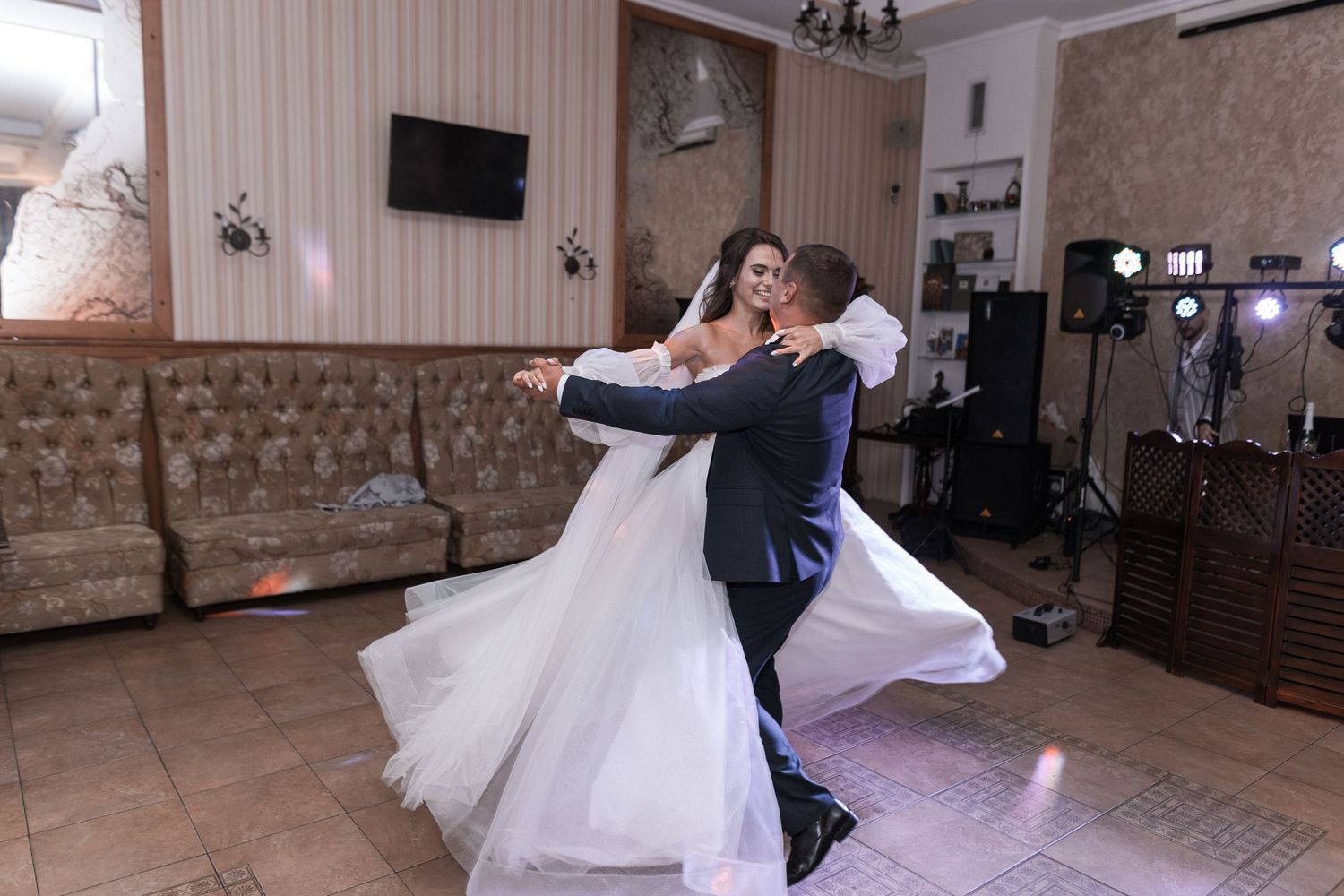A couple performs their first dance in a reception hall with a flowing white wedding dress spinning elegantly.