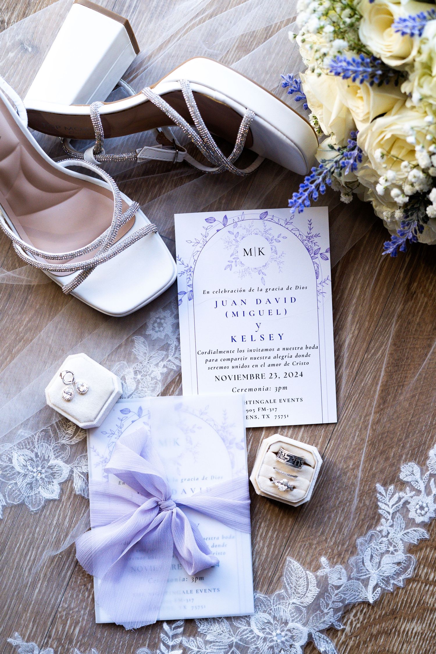 Wedding details including invitation, rings, shoes and delicate lace accents in soft purple and white tones.