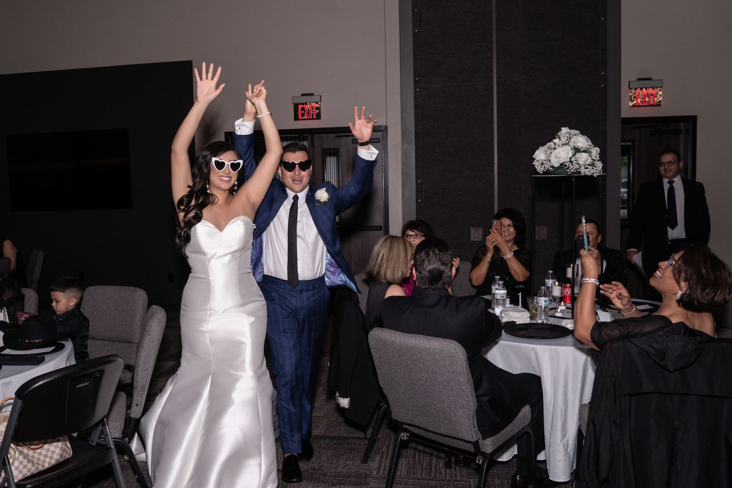 Wedding guests dance and celebrate at a reception while a bride in white gown joins the festivities on the dance floor.
