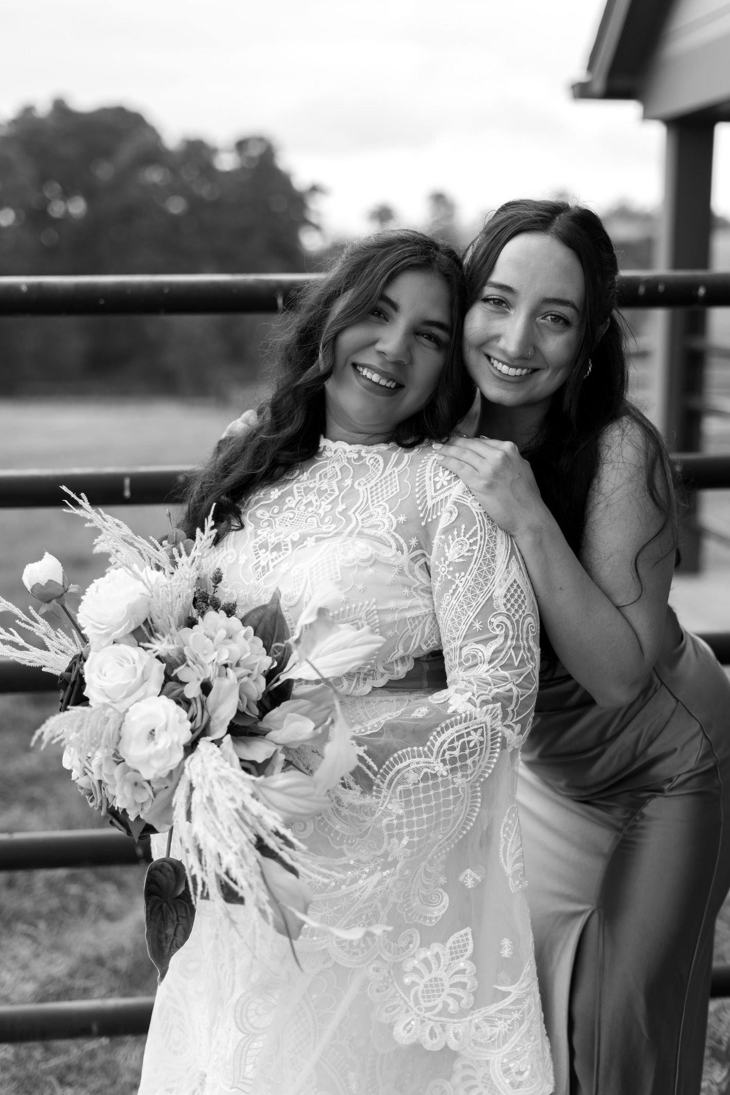 Bridal party poses with floral bouquets against rustic backdrop.
