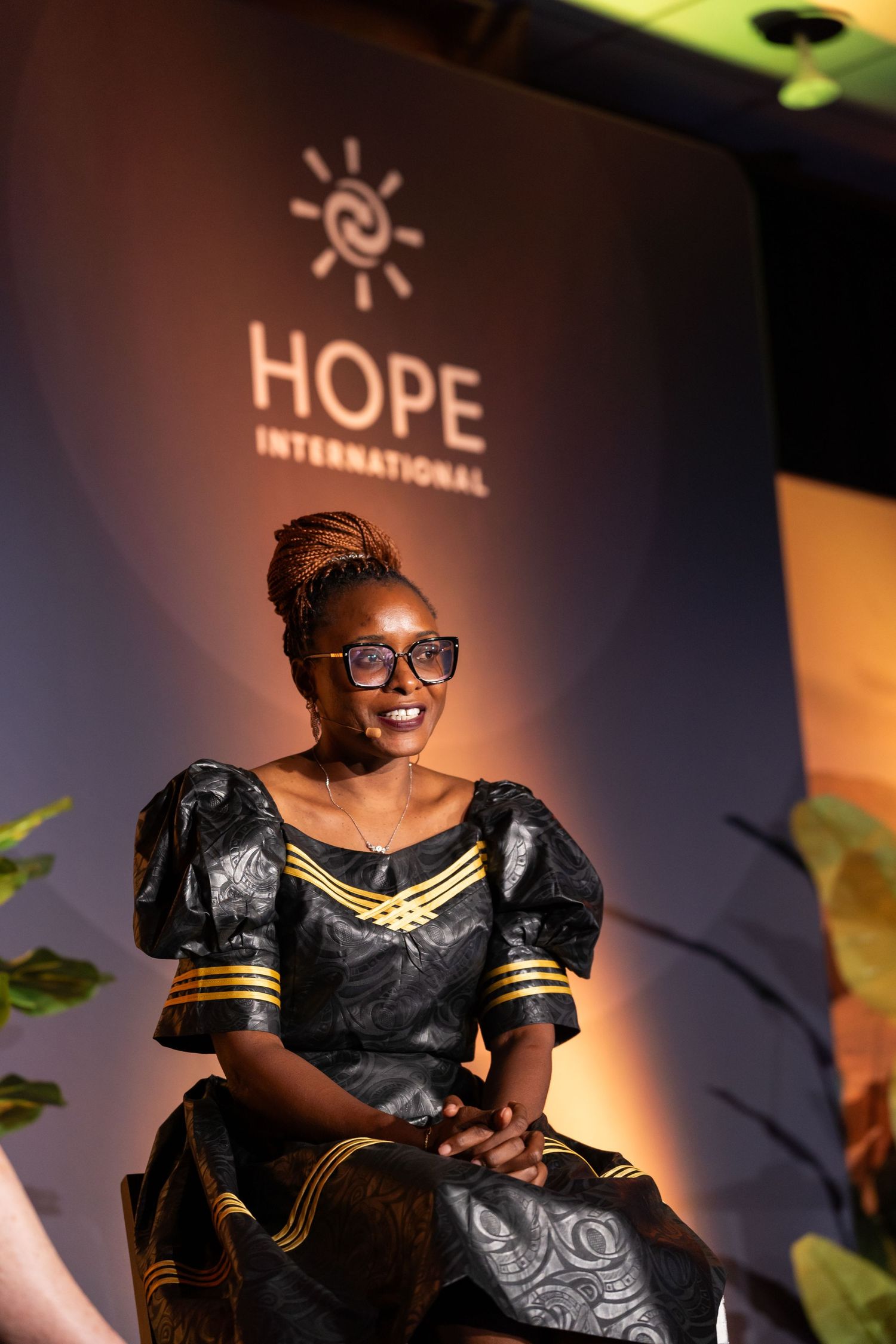Speaker in traditional African dress presents at HOPE International event.