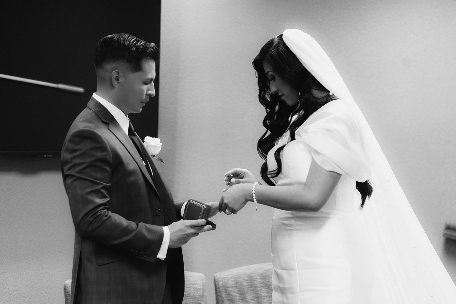 Black and white wedding photos showing a couple exchanging rings during their intimate ceremony.