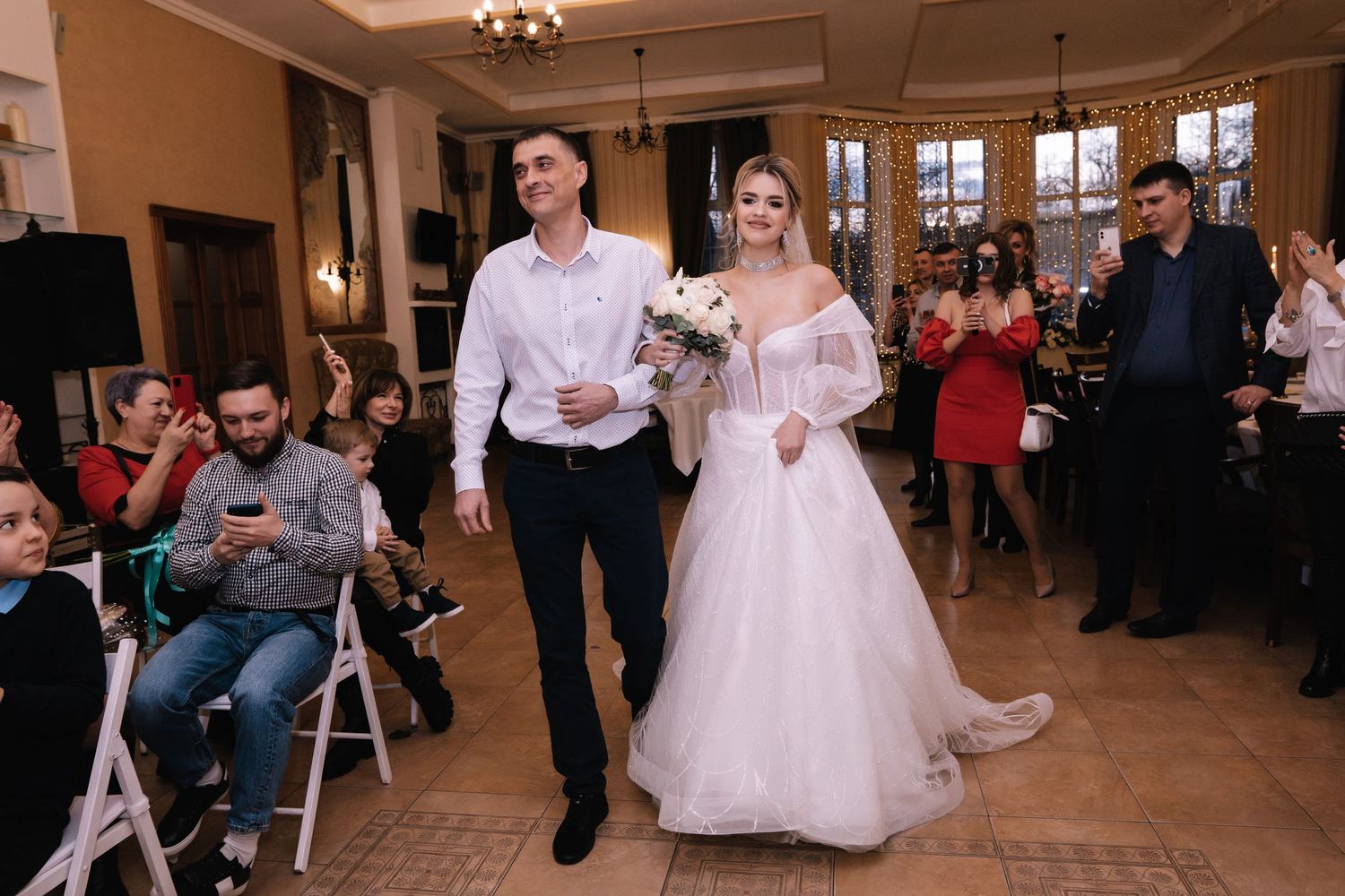 Wedding guests dance and celebrate on the dance floor at an indoor reception venue.