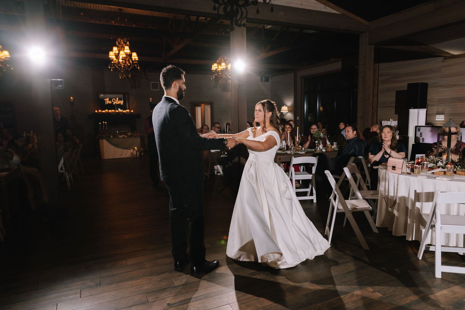 Wedding couple and guests dancing at dimly lit evening reception.