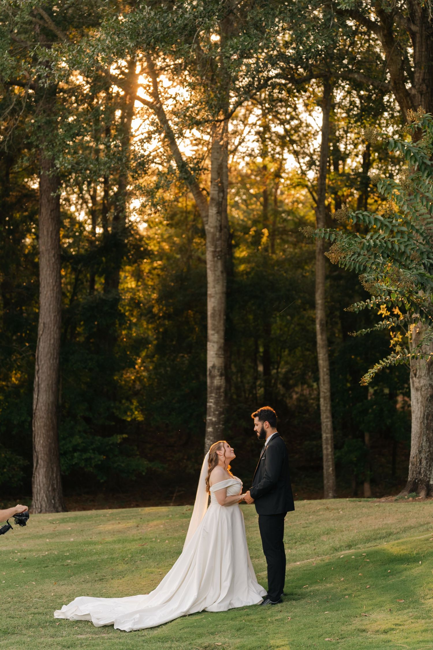 A romantic sunset wedding photoshoot in a wooded area with golden light filtering through tall trees.