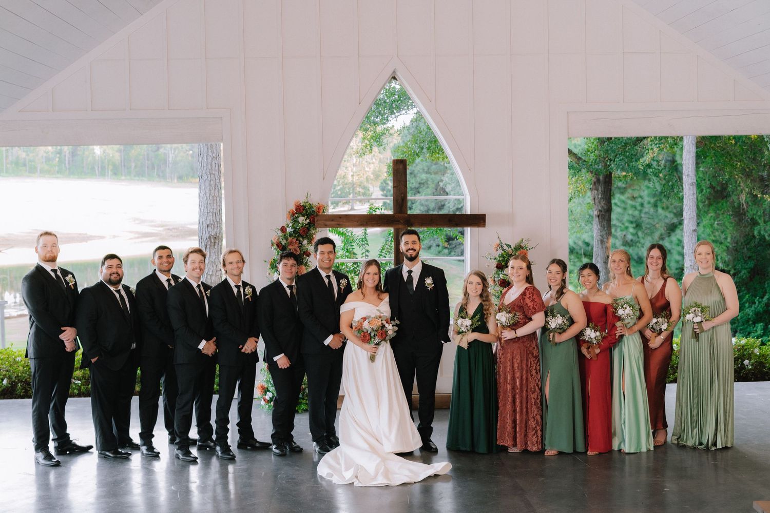 Wedding party members in formal attire pose together against a white backdrop for group photos.