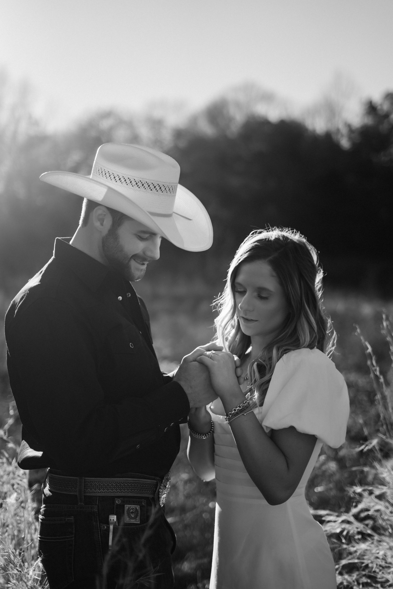 Black and white romantic photos of a couple in a field with dramatic lighting.