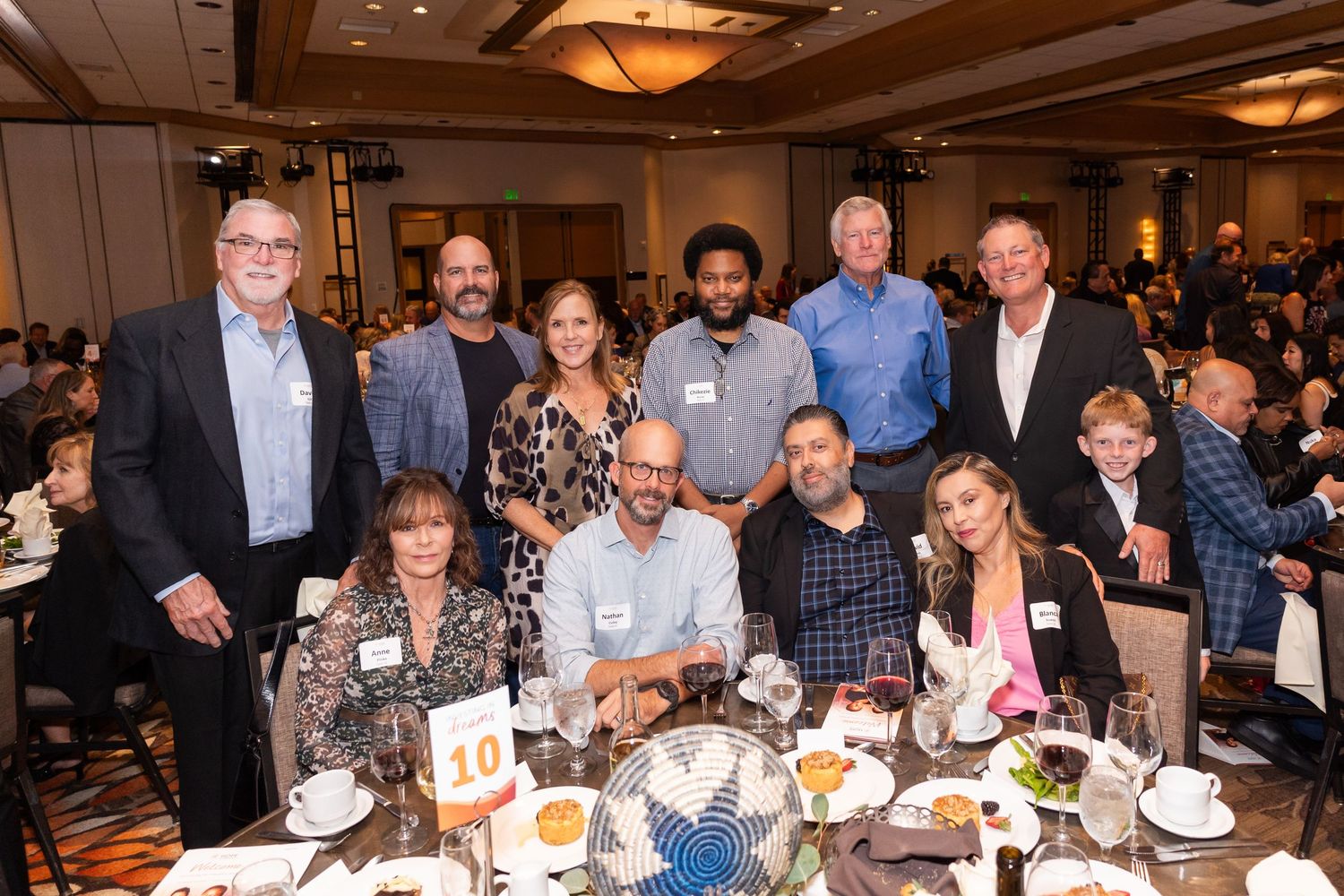 Large group gathered around dining table at formal banquet event.